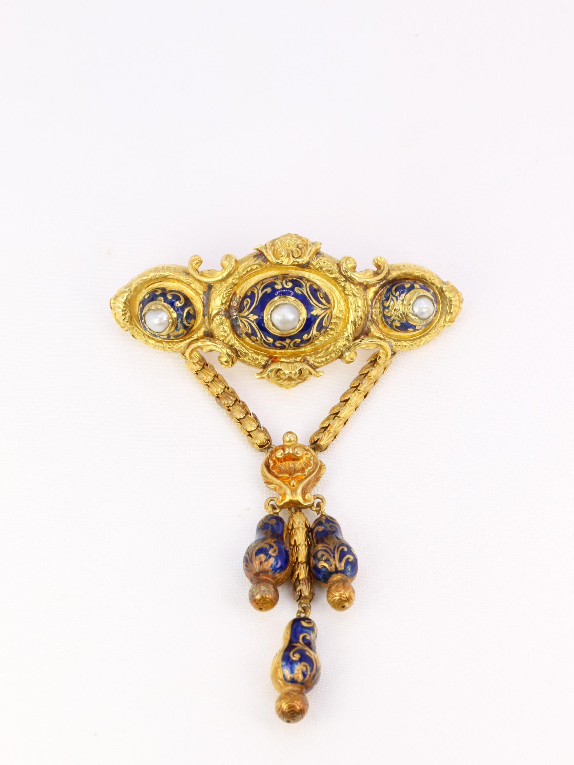 18Kt (750°/°°) yellow gold victorian brooch featuring an upper element decorated with arabesques and foliage and three oval parts enhanced with blue enamel and each centered with a fine gray pearl. This element supports a lower part composed of