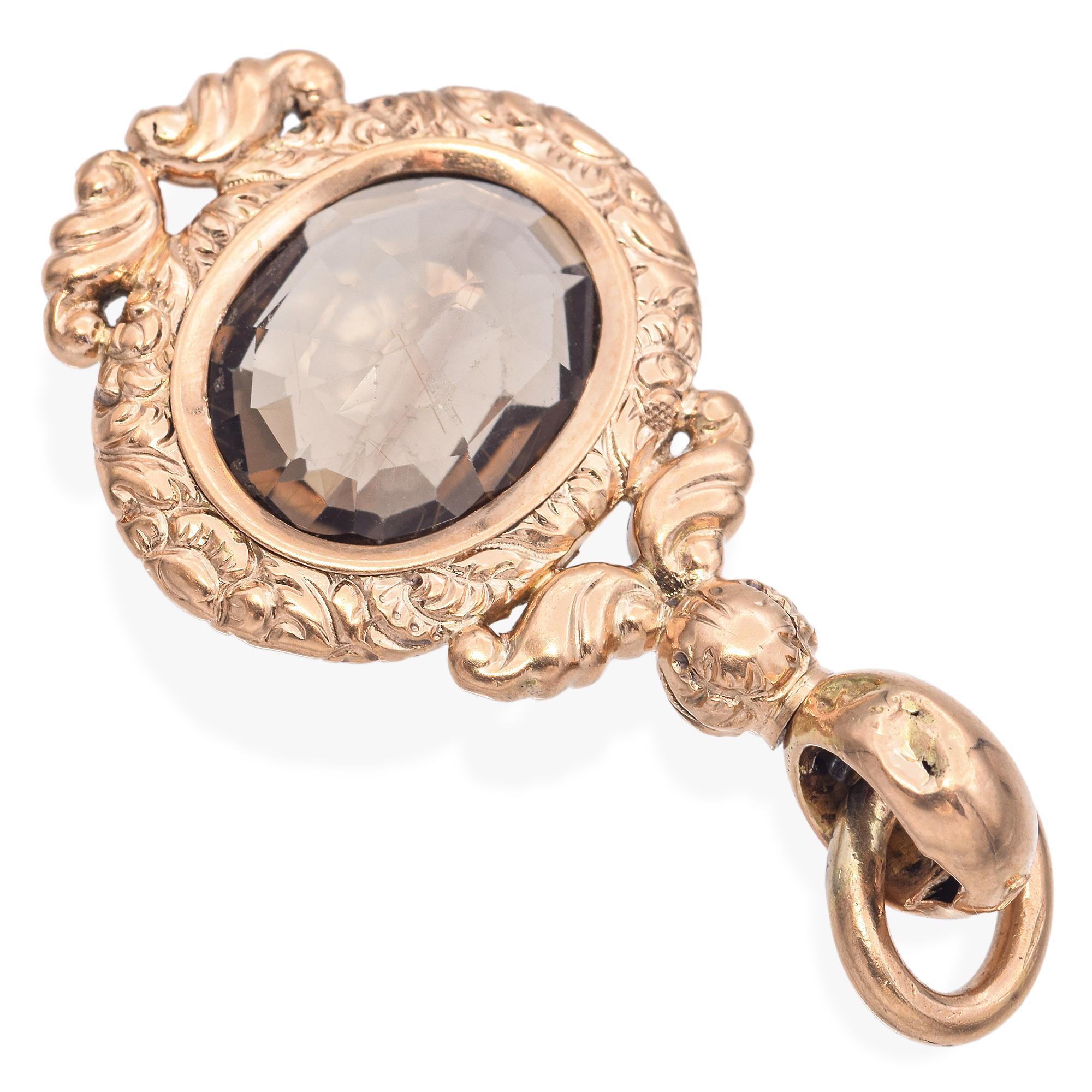 Un porte-montre orné d'un quartz fumé à facettes serti dans un cadre en or aux détails complexes. Le motif comprend des volutes et une boucle d'attache.

Poids : 5,6 grammes 
Pierre : 5ct Smoky Quartz 
Dimensions : 36,5 x 20,7 x 6,5 mm
Métal : cadre