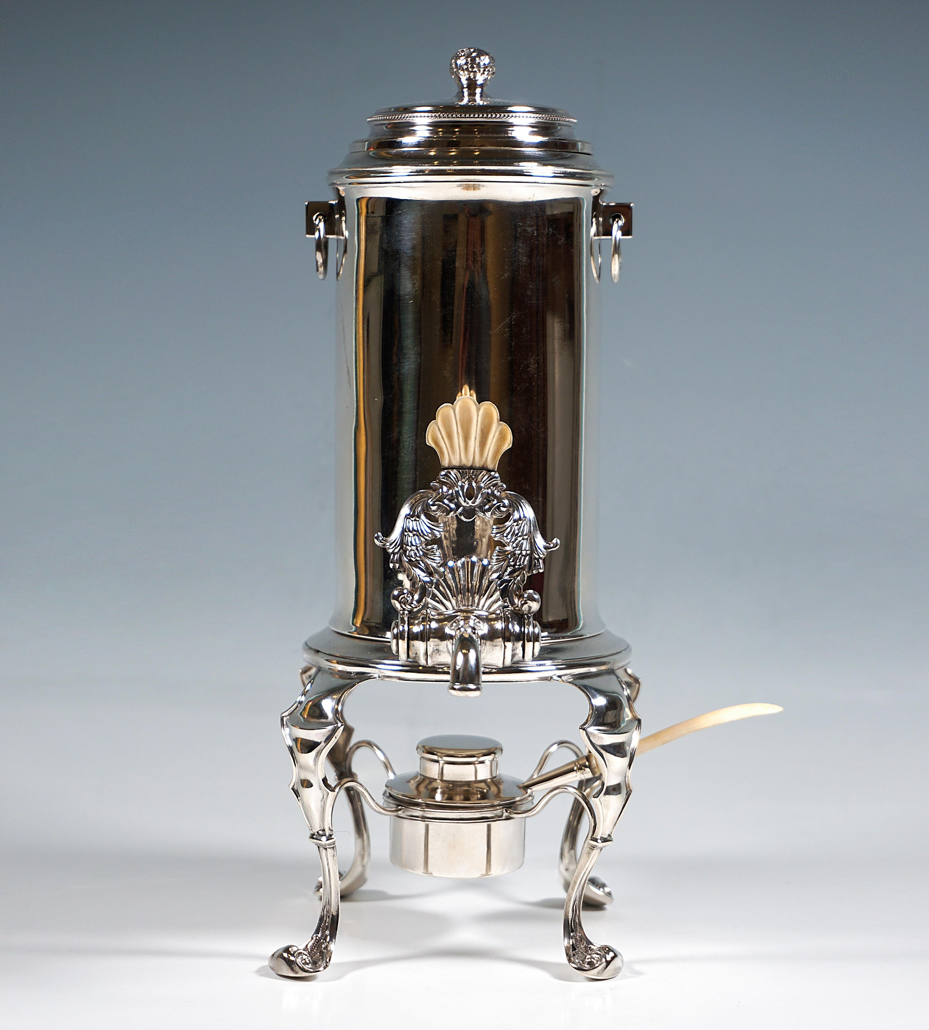 Consists of a hot water vessel with a lockable spout, a silver frame and a burner.
Cylindrical vessel with two drop ring handles, removable lid with acanthus knob, pouring lever with flower bouquet decoration and bone handle in the shape of a shell;