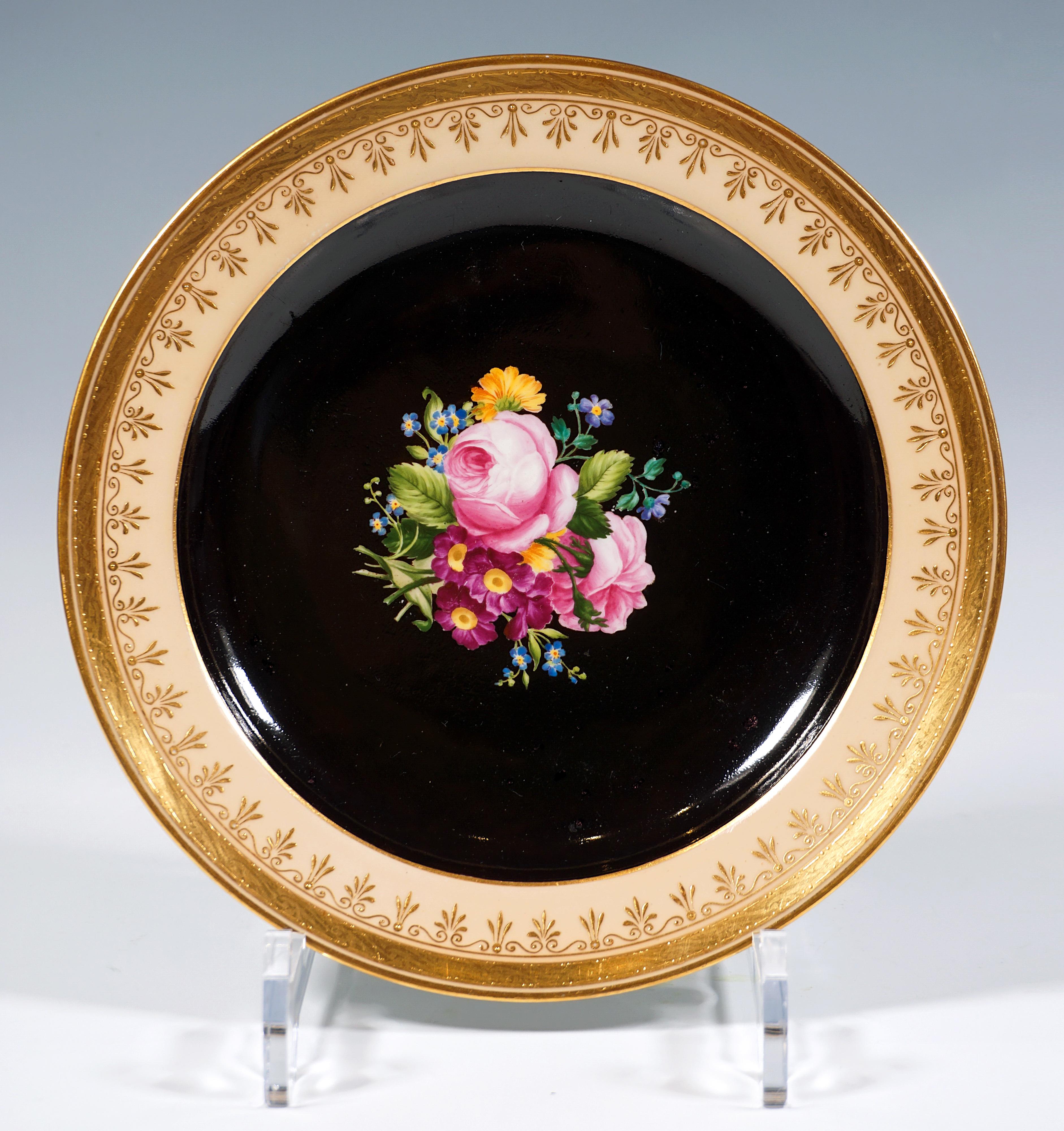 Plato de porcelana con ilustración botánica pintada y policromada:
En el centro, un ramo finamente pintado con rosas y nomeolvides sobre fondo negro.
El borde del plato es de color salmón con un borde ancho dorado con bandas de puntos y líneas