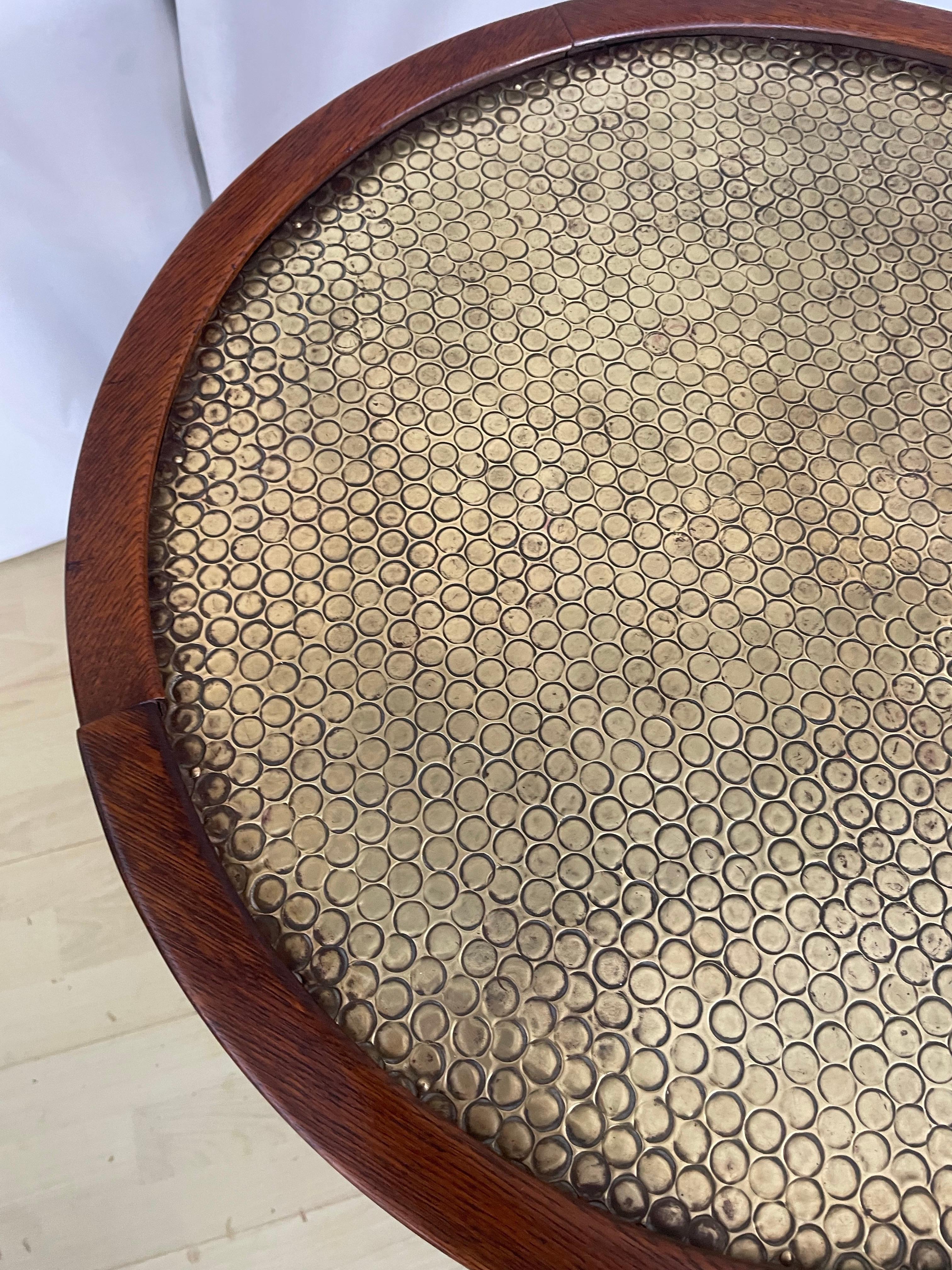 Mesa antigua, elegante y con estilo, con tablero de latón, borde moldurado y cuatro patas perfiladas unidas por un estante y terminadas en base de latón y patas almohadilladas. 