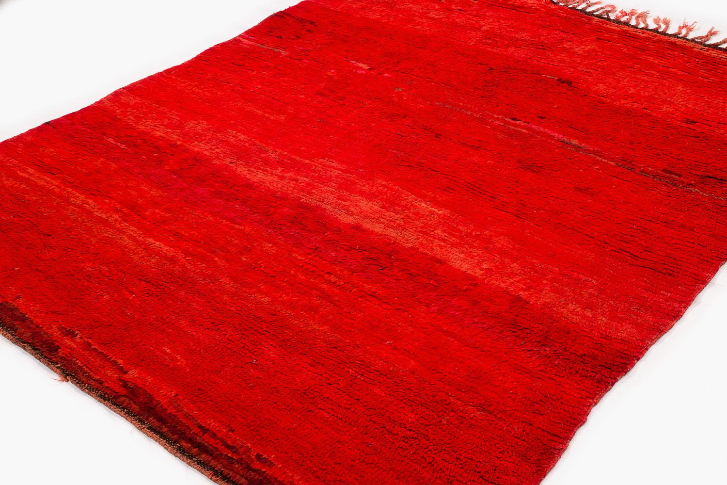 Alfombra marroquí antigua de colección en excelente estado. Se trata de una alfombra sólida de color rojo intenso que presenta infinitas variaciones en el tinte, lo que le confiere un efecto cautivador, sobre todo con luz natural. Es una auténtica