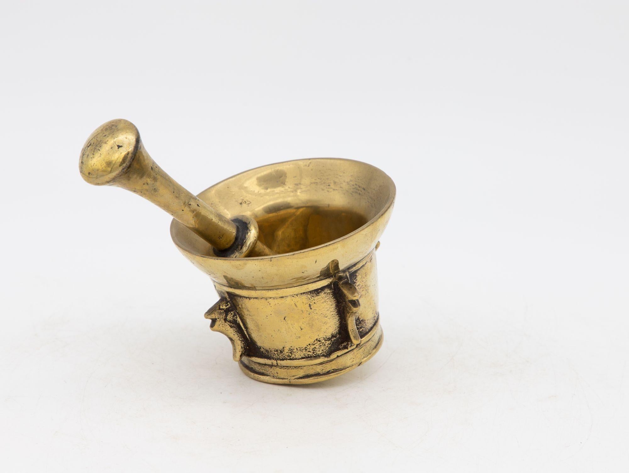 This early 20th-century mortar and pestle is made of brass with an honest patina. Both the mortar and pestle are traditional in style. The mortar has a classic bell-shaped body and the pestle has two flat ends. Brass mortar and pestles were used for