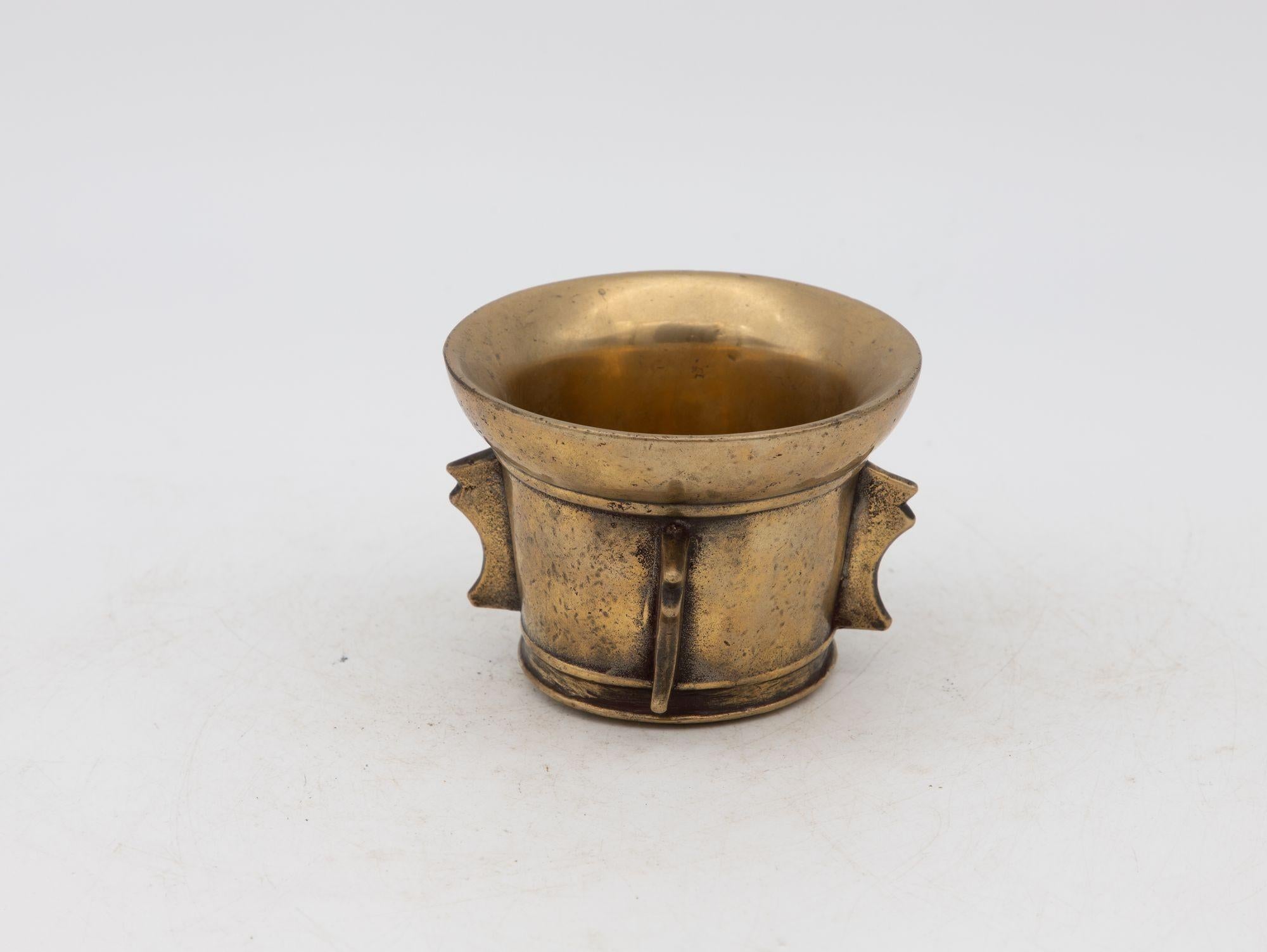 This early 20th-century mortar is made of brass with an honest patina. The mortar is traditional in style. The mortar has a classic bell-shaped body. Brass mortar and pestles were used for both food and apothecary. This makes a lovely decorative