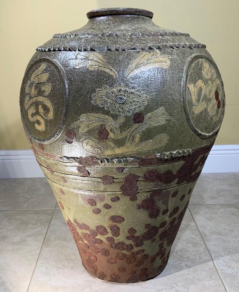 Un pezzo accattivante di arte ceramica cinese! Questo grande e pesante vaso in gres è caratterizzato da uno splendido smalto verde intenso e marrone ricco su una decorazione in rilievo sapientemente intagliata, che lo rende una dichiarazione