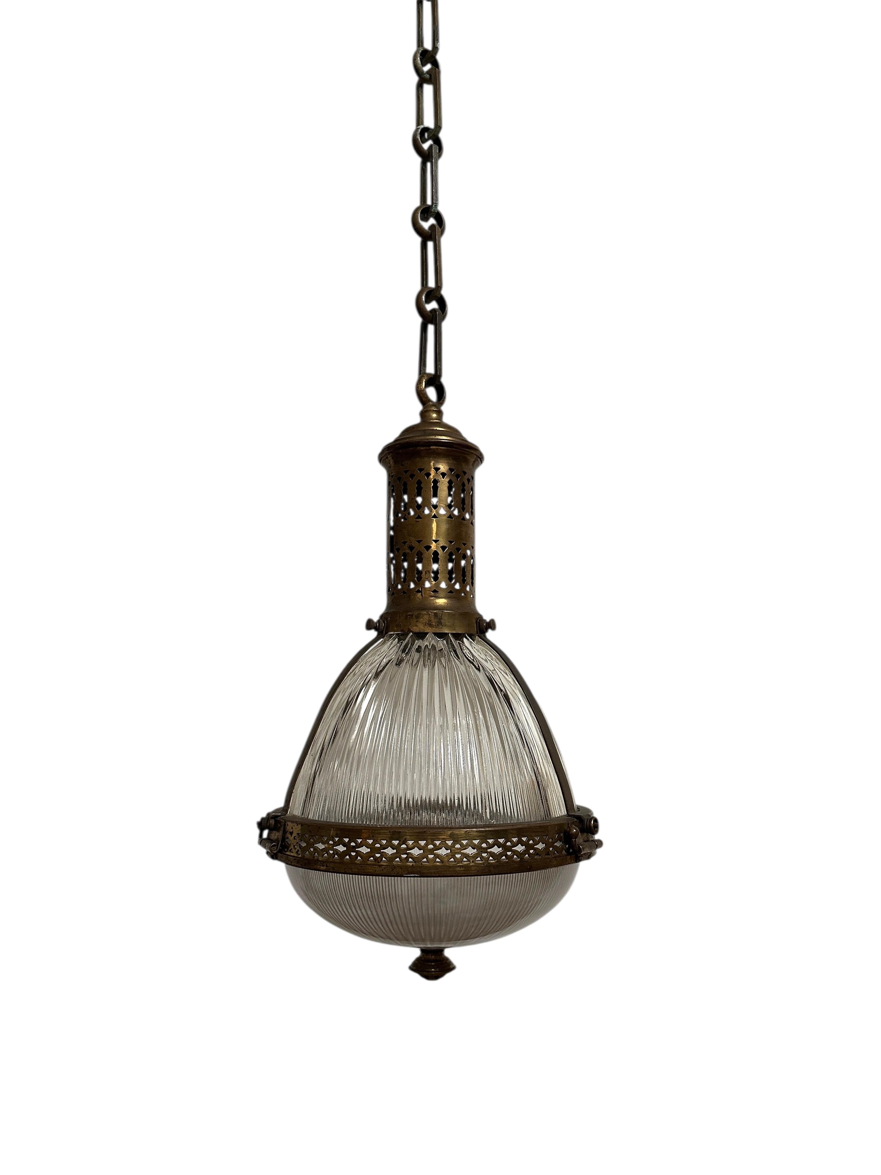 - A beautiful and extremely rare caged Holophane pendant with original chain and ceiling rose, France circa 1920.
- Heavy brass cage housing two sections of prismatic glass, both stamped Holophane.  The cage is hinged around the rim in order to open