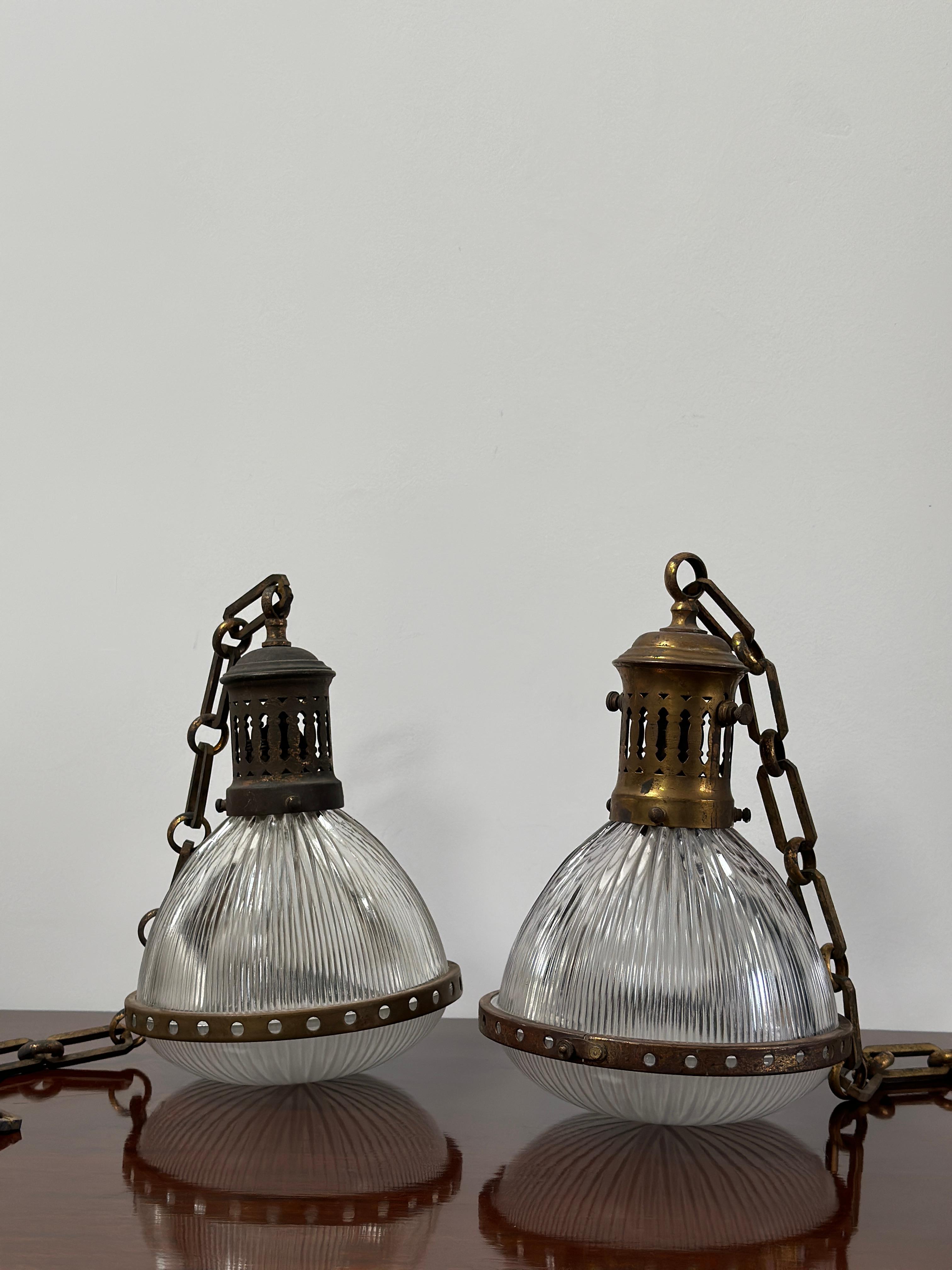- A wonderful pair of rare caged brass Holophane pendants, France circa 1920.
- The pendants consist of a Holophane stamped glass shade and separate dish held together by a circular patinated brass ring.  
- A decorative gallery with adjustable bulb