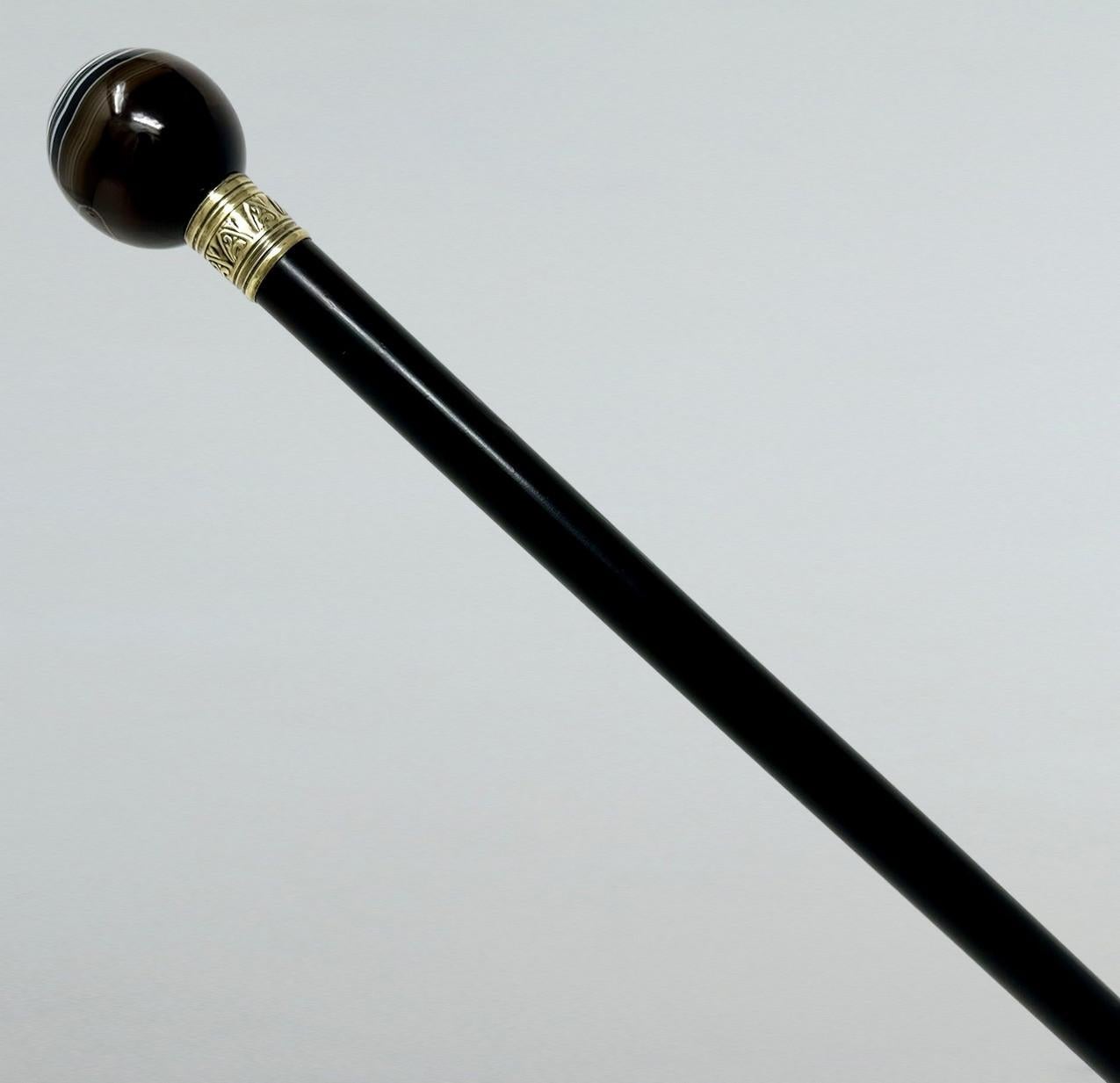 Very Stylish Fine Quality Polished Ebony Lady’s or Gentleman’s Walking Cane of English origin, late Nineteenth Century. 

The extremely elegant ball grip in carved Banded Agate above a silver gilt decorative collar in the Art Nouveau taste  