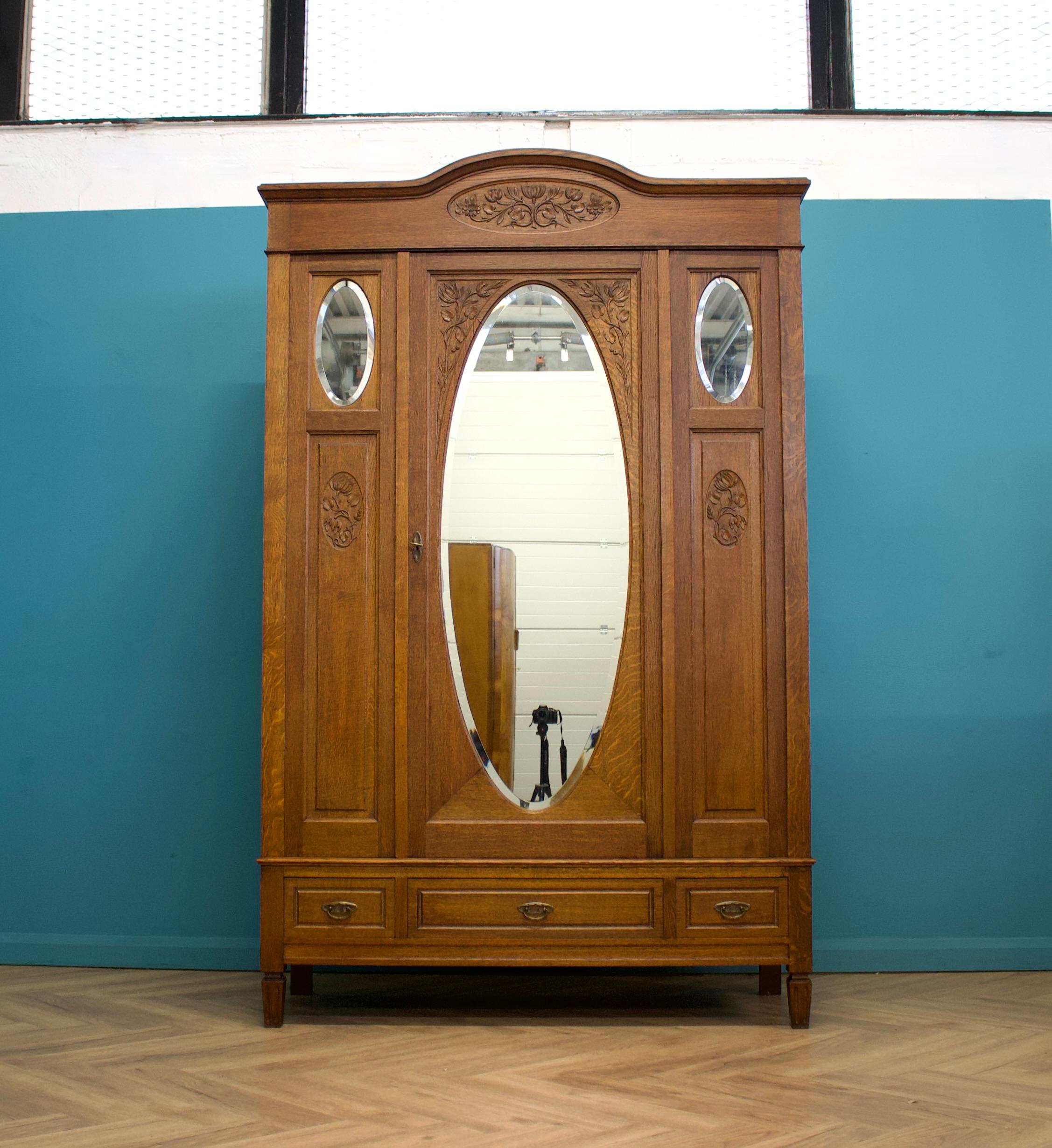 Un imponente armadio in rovere massiccio in stile Art Nouveau francese, realizzato a mano all'inizio del XX secolo.

Le curve e i motivi floreali sono tipici dello stile Art Nouveau.


C'è un'ampia porta a specchio che si apre per rivelare un