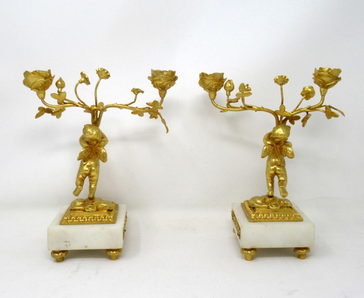 A fine pair of stylish and imposing French ormolu and cream statutory marble twin light table or mantle candelabra of outstanding quality, mid-late 19th century. 

Each with a central standing ormolu solid bronze Cherub holding a loft a two branch