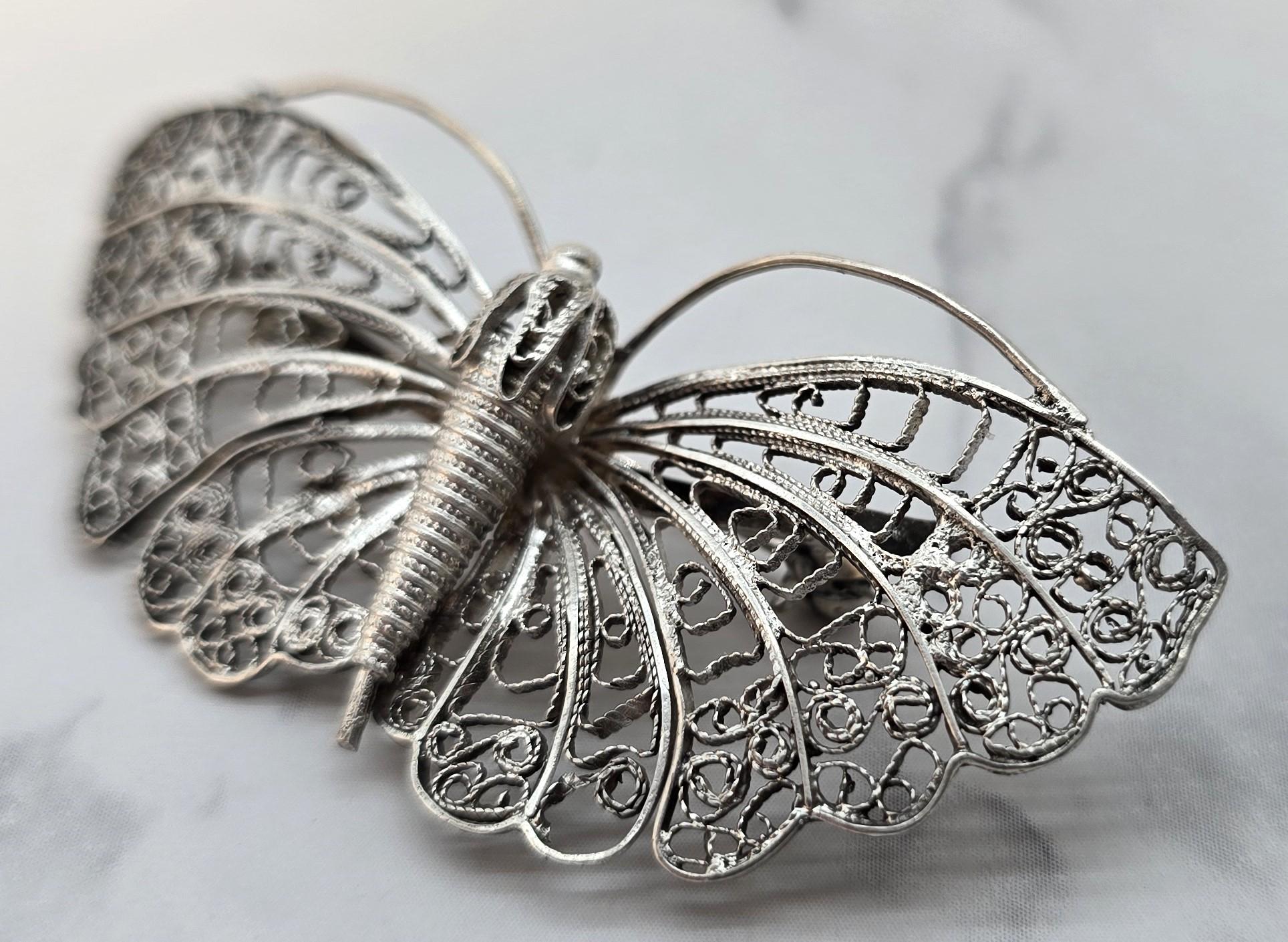 Este hermoso broche de mariposa de filigrana de plata data de hacia 1930 y es muy probable que proceda de Malta o Italia, donde se fabricó esta fina joya.  el trabajo era popular.

El broche tiene un pasador con bisagra que lleva estampadas las