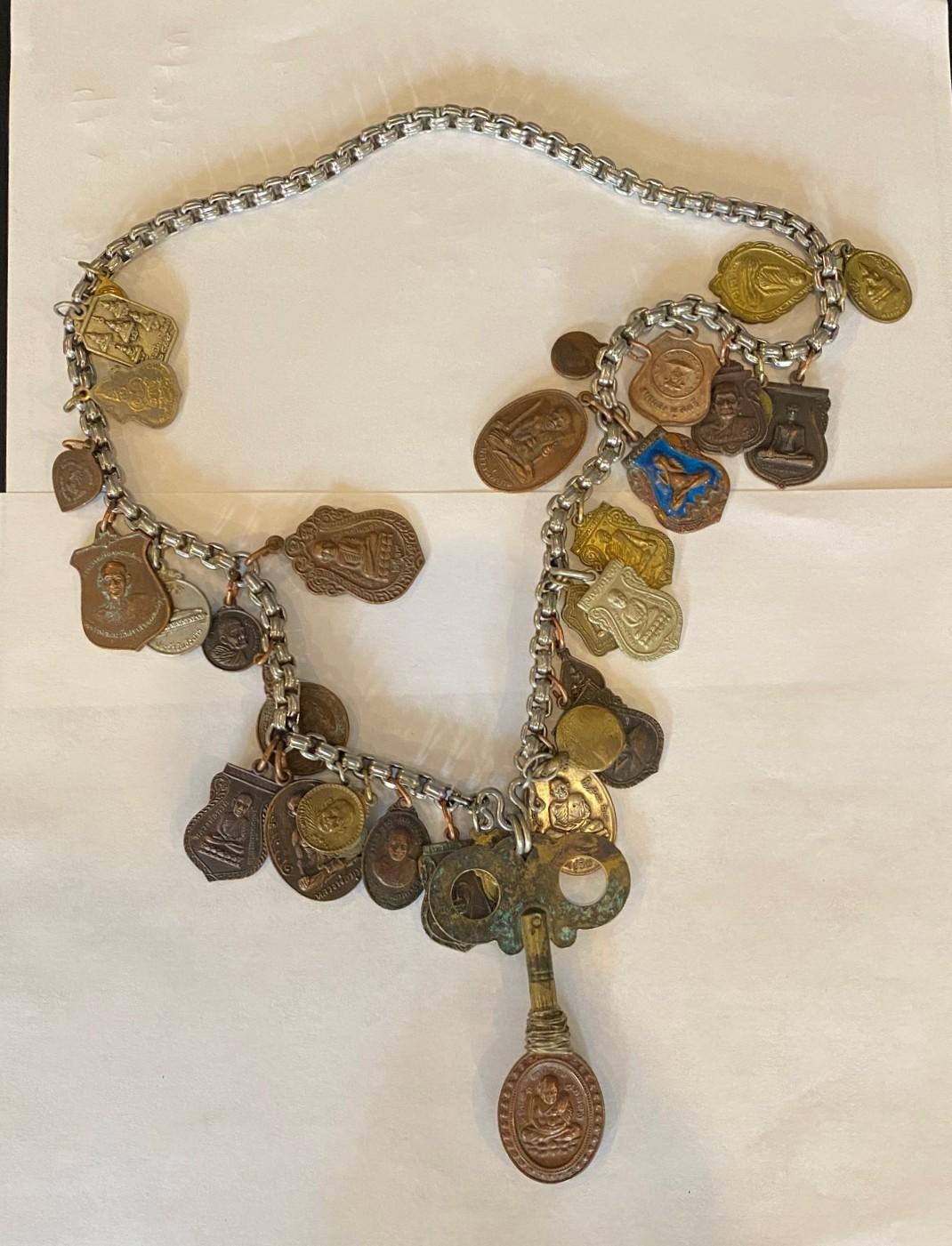A wonderful, quite special and unique Thai (Thailand) Buddhist sacred amulet/charm necklace featuring 32 silver and gold toned amulets/charms plus one main larger key shaped center piece, each with images of venerated monks, Buddha or holy places -