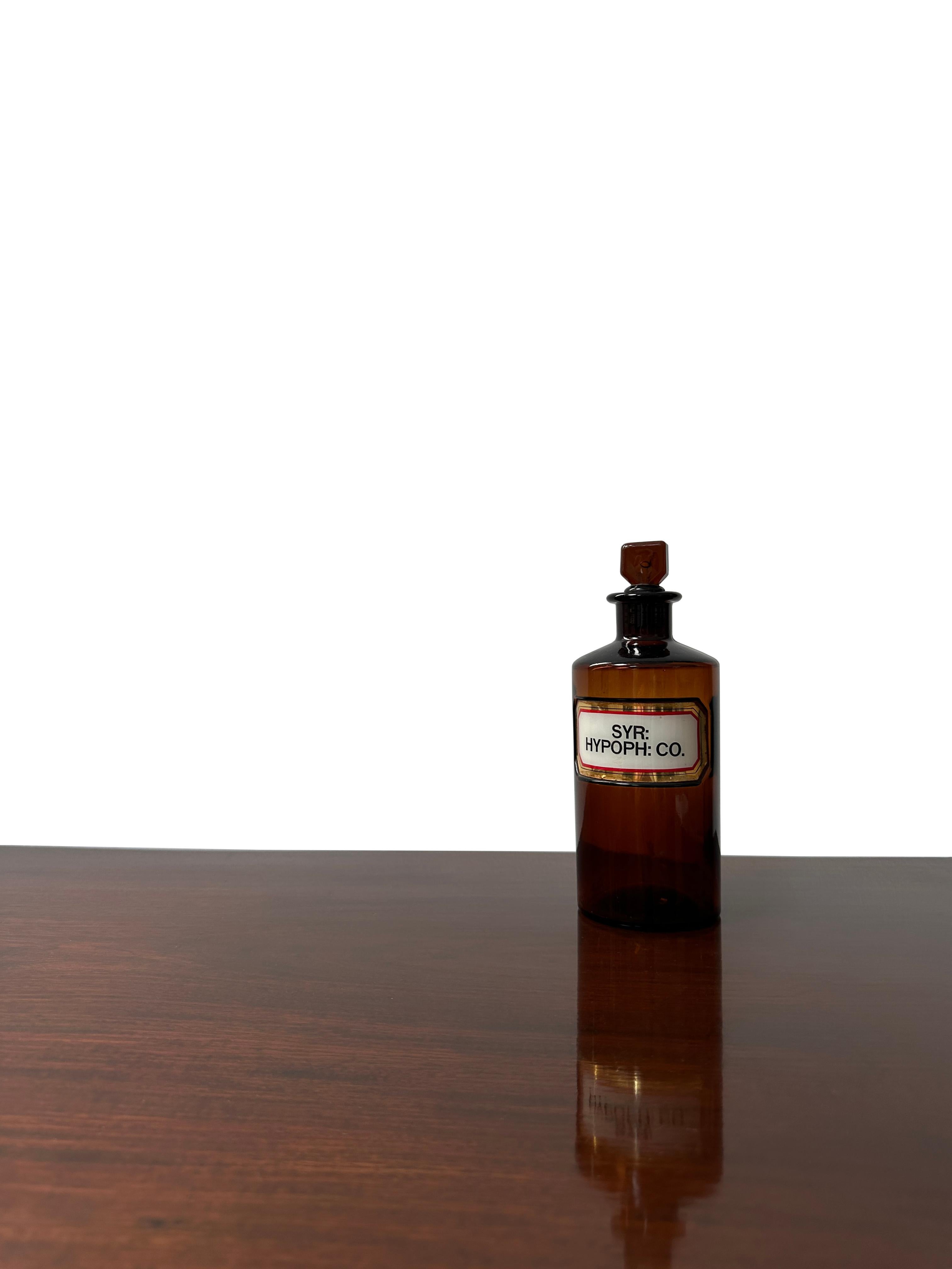 - Une belle bouteille de pharmacie victorienne en verre brun, vers 1900.
- Excellente plaque en verre, lettrée et peinte en doré sur le devant et avec le bouchon en verre d'origine. 
- La fine étiquette blanche, dorée et rouge recouverte d'une