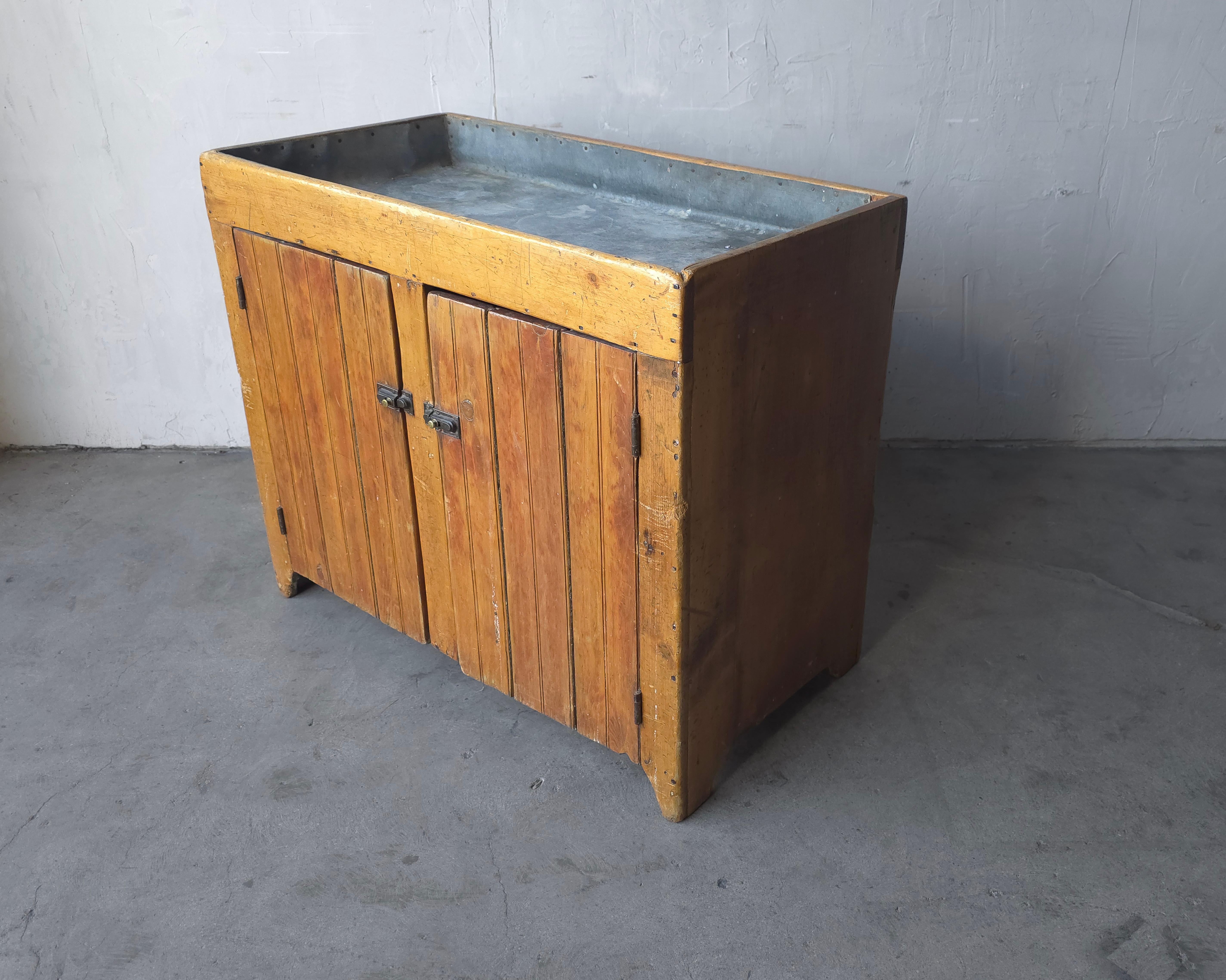 Un bellissimo esempio di lavello antico a secco.  Questo pezzo è bellissimo, con innumerevoli decenni di carattere dovuto all'età e all'uso.  Realizzato in legno massiccio con rivestimento in metallo galvanizzato.  Dietro entrambe le porte c'è un