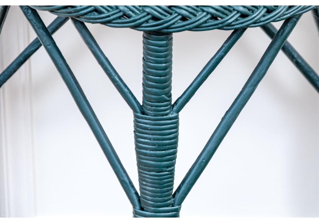 Ein Beistellstuhl mit hoher Rückenlehne und ein demilunfarbener Beistelltisch in dunkler jägergrüner Farbe. Der Stuhl hat eine runde Sitzfläche und eine hohe, geformte Rückenlehne mit Schnörkeln und Gitterkonstruktion. Die geschwungenen Vorderbeine