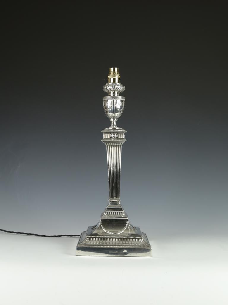 Descrizione

Questa imponente lampada da tavolo in argento antico con marchio di fabbrica vanta una base quadrata con fasce scanalate inferiori e sezioni elegantemente inclinate ornate da intricati dettagli in rilievo di drappi e festoni. La lampada