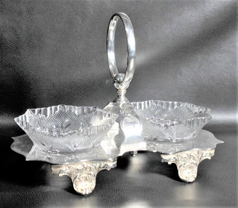 This antique silver plated condiment set was made by Walker & Hall of Sheffield England in circa 1900 in the period Victorian style. The holder has ornately cast feet and some engraving on the side supports leading up to the round handle. The