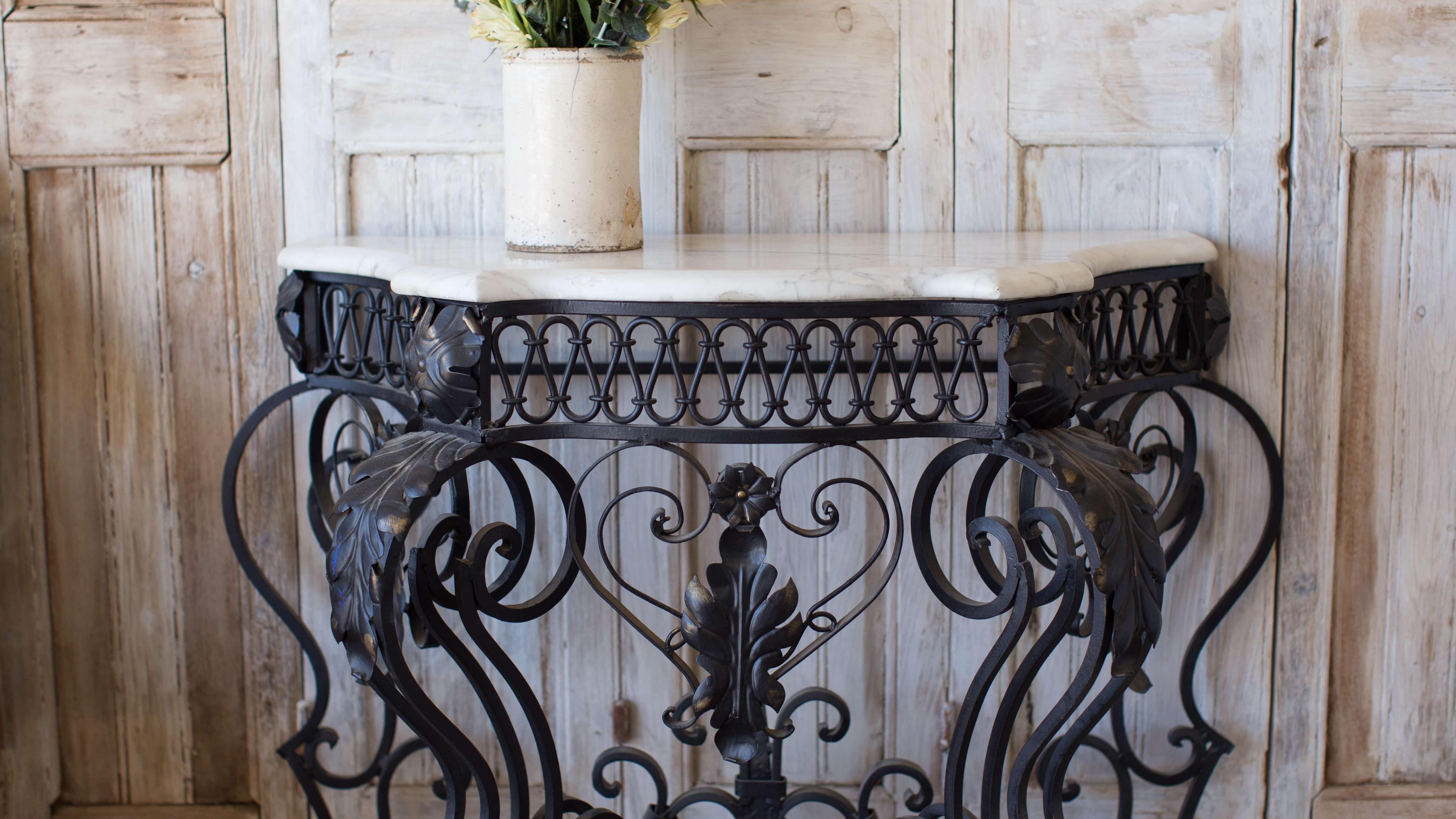 Romantic French antique wall console with white marble top and soft edge. Beautiful hand-forged scrolling details in wrought iron and painted black with the slightest hints of gold.