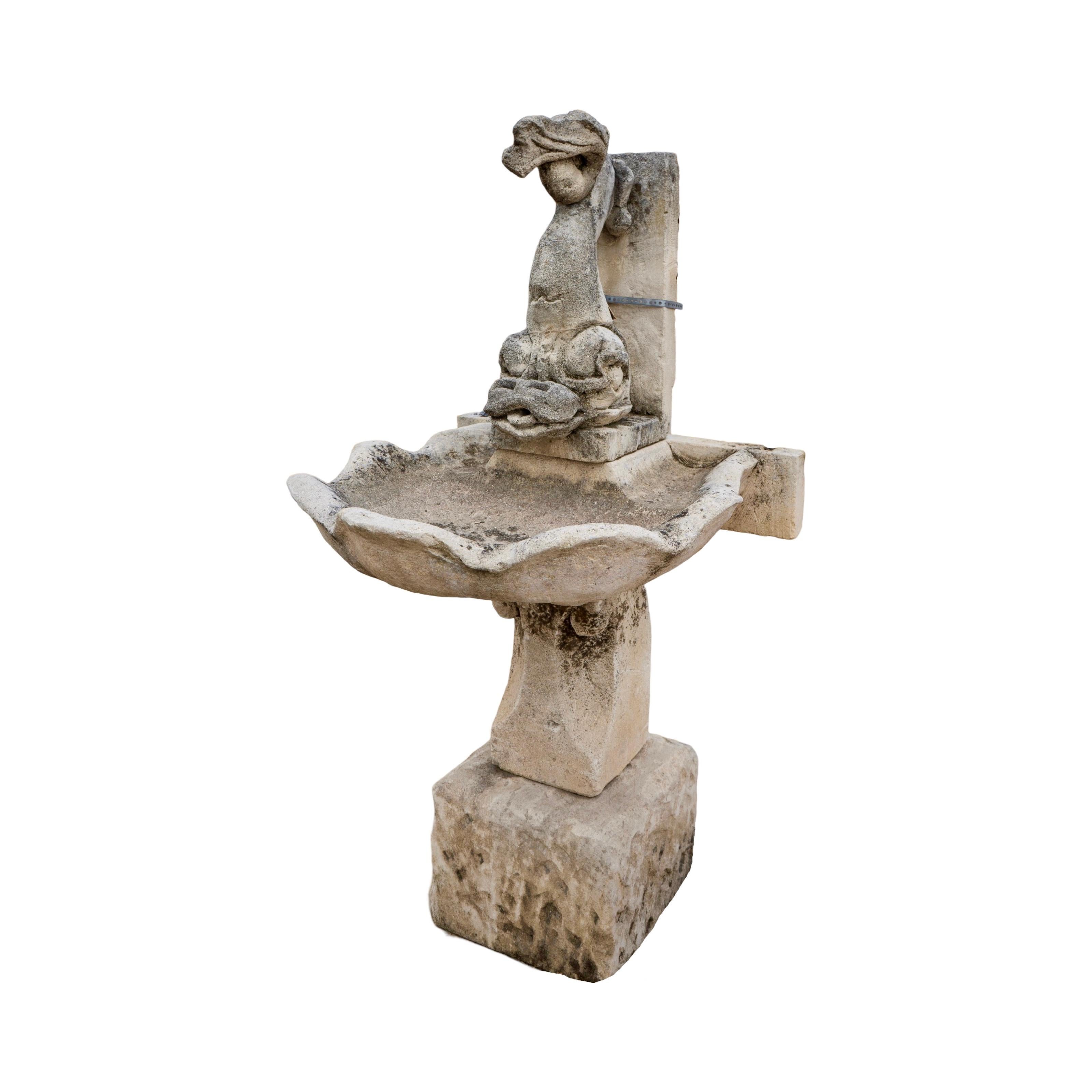 Eleva tu espacio exterior con esta antigua fuente de pared de piedra caliza francesa del siglo XIX. Con un mítico pez tallado como pieza central, el agua cae suavemente en cascada en una pequeña pila diseñada para parecerse a una concha marina,