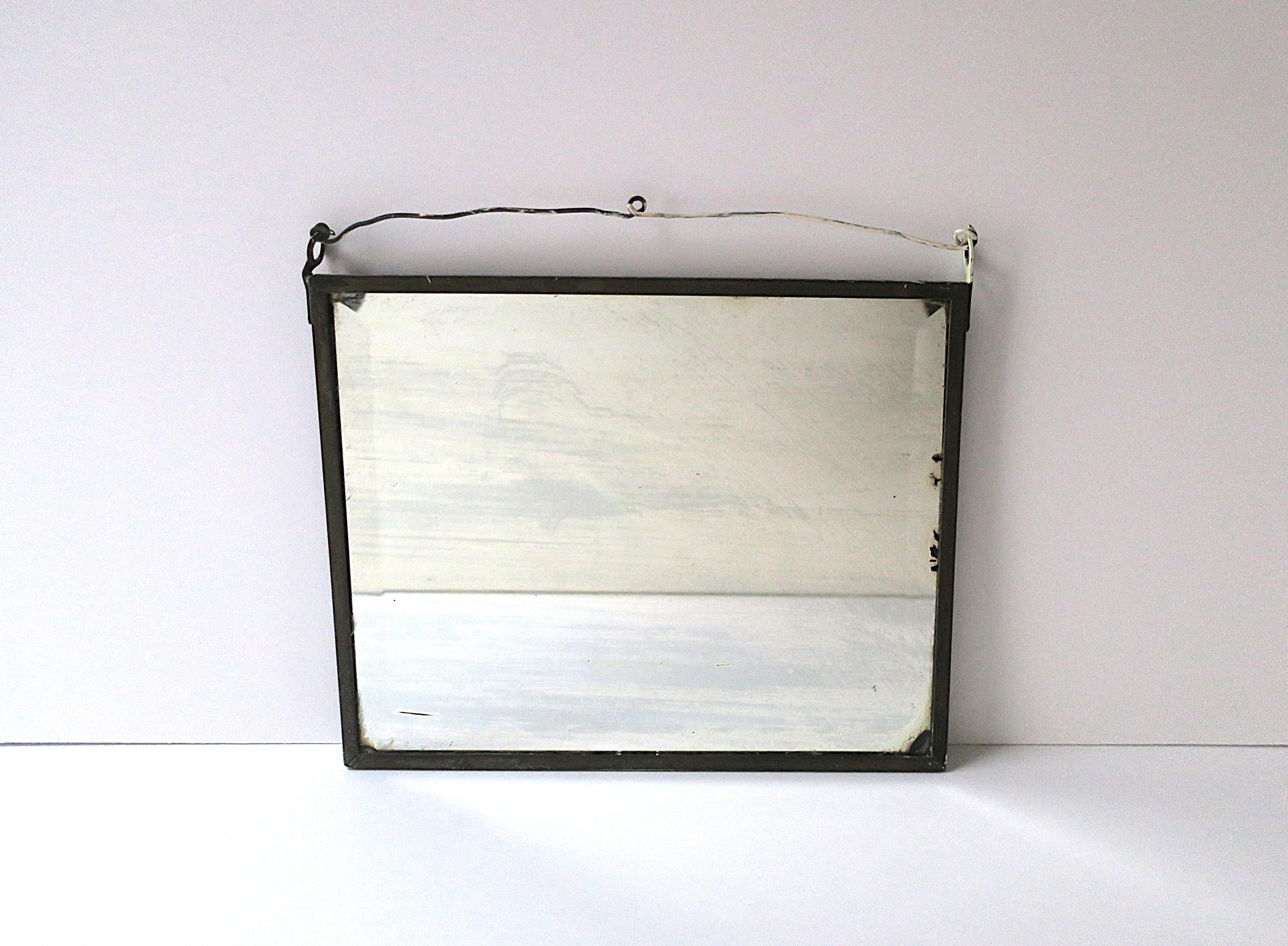 An antique wall mirror shaving vanity mirror, circa early-20th century. Mirror is rectangular, beveled, embraced by metal frame and metal wire across top for hanging. Mirror measures: 10.13