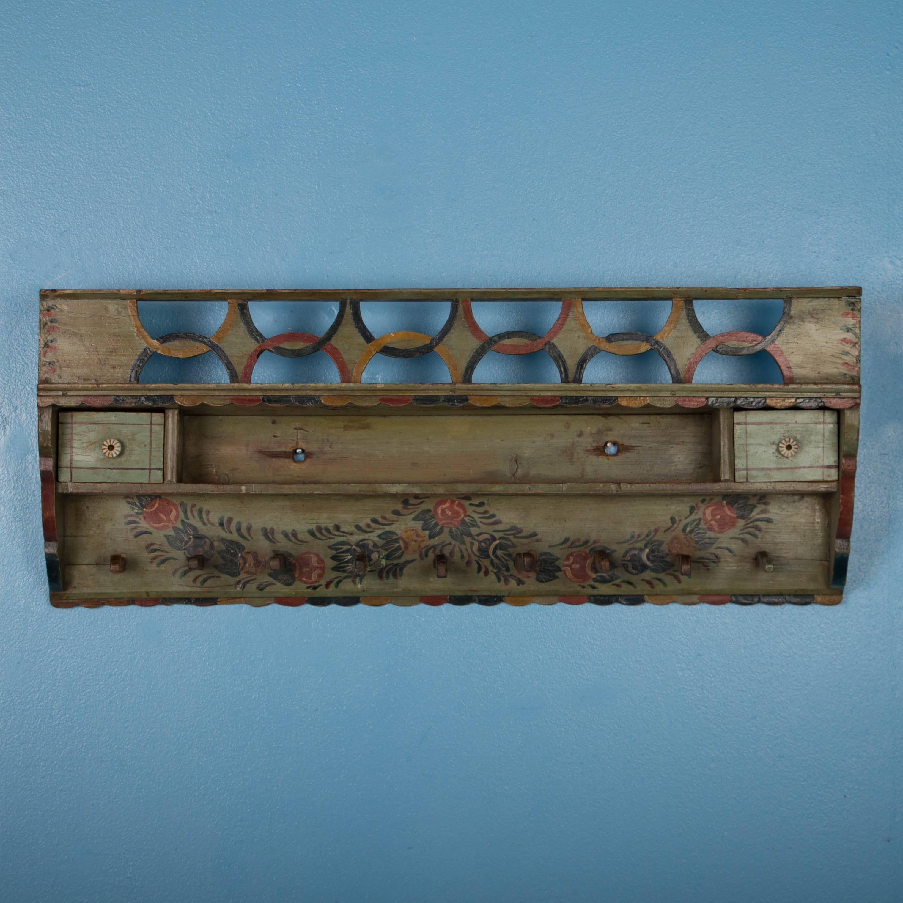 This delightful hanging shelf / rack still maintains its original green paint, with flowers and other details in red, blue, yellow and green. Painted racks were common elements in European country homes, however the exceptionally fine painted