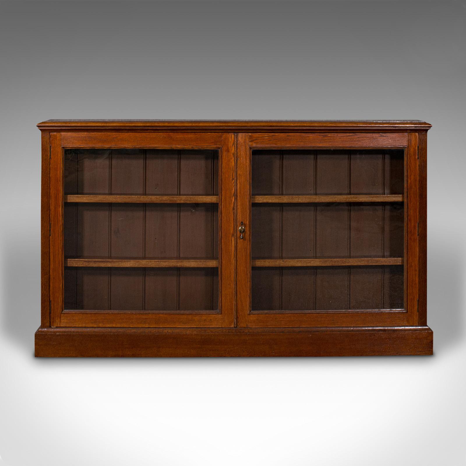 This is an antique wall standing display bookcase. An English, oak and glass library cabinet, dating to the Victorian period, circa 1870.

Appealing library showcase, the narrow profile usefully versatile
Displays a desirable aged patina and in