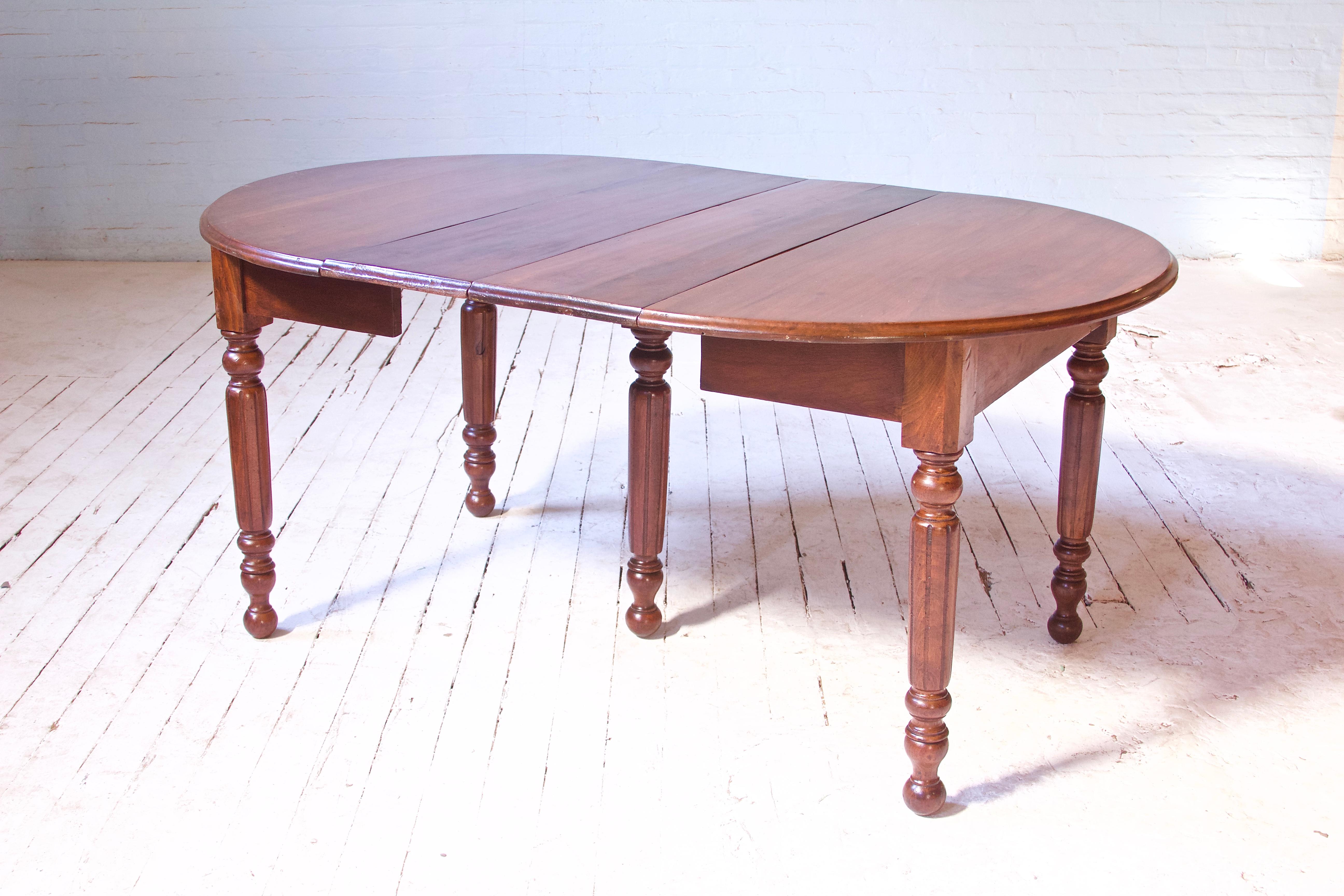 Attractive and handmade 19th century Walnut extension dining table, made in the U.S in the Irish provincial style. This unique expression of craft features lovely hand-turned and fluted legs, ogee-moulded top detail, and hand-cut dovetail extension