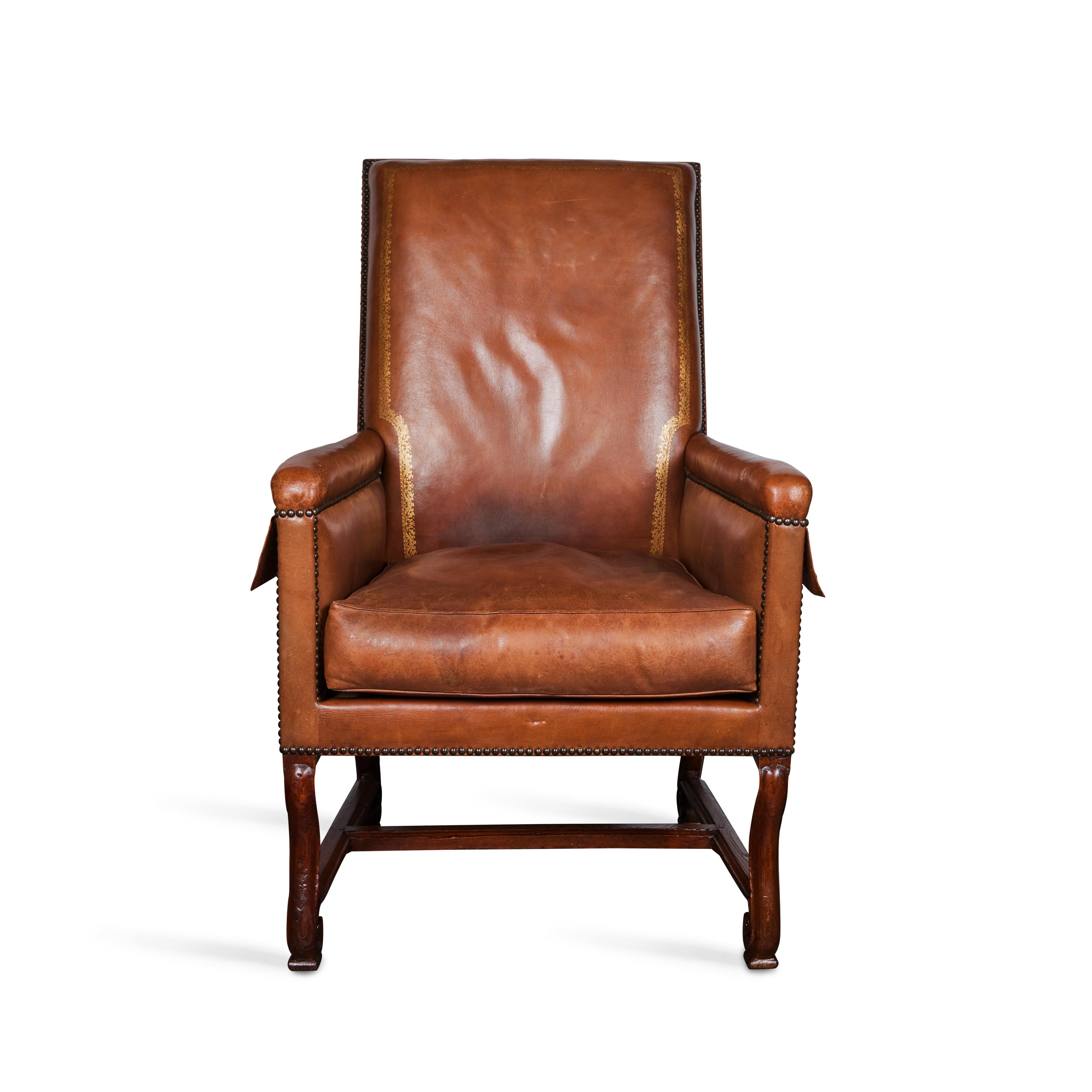 Hand carved walnut armchair with original gold embossed trimmed leather and nail heads.  Side pockets.  