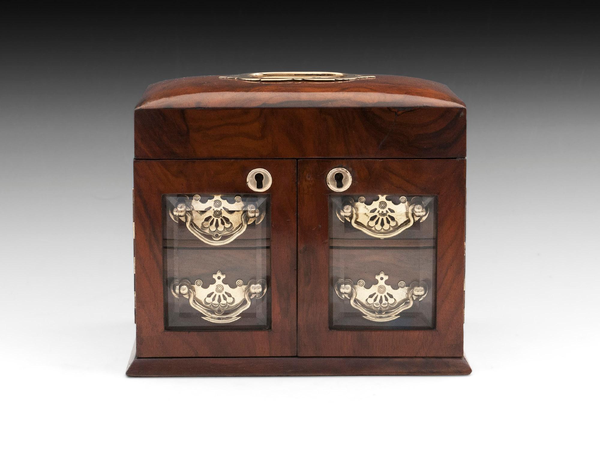 Antique walnut jewelry cabinet with brass carry handle and beveled glass doors to the front.
Once unlocked the lid can be lifted to reveal three padded jewelry compartments, including two that can be used for rings, earrings or cufflinks. 

With