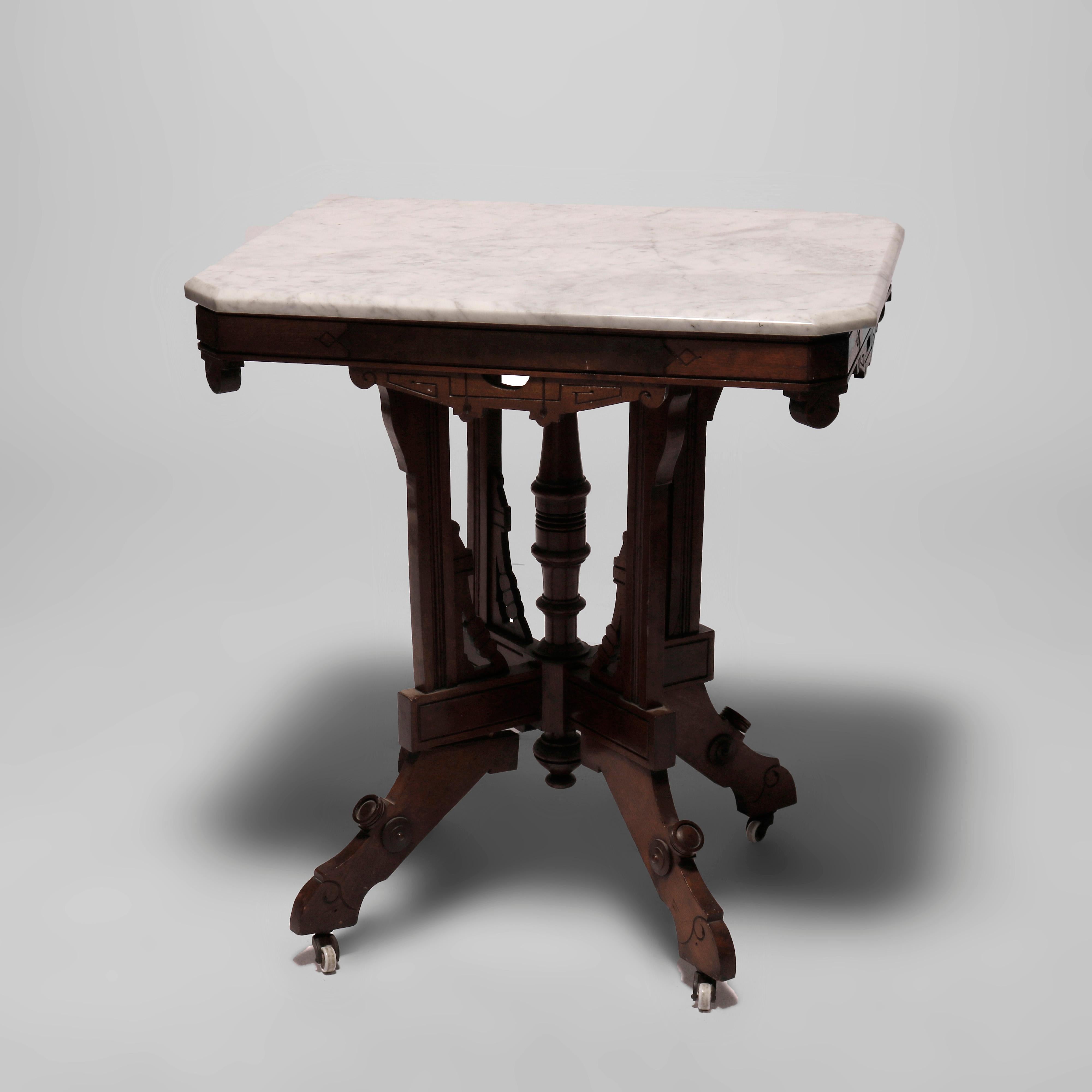 An antique Eastlake parlor table offers beveled clip-corner marble top over walnut base having burl insets, shaped skirt, four supports with decorative corbels surrounding turned column, and raised on stylized cabriole legs, incised decoration