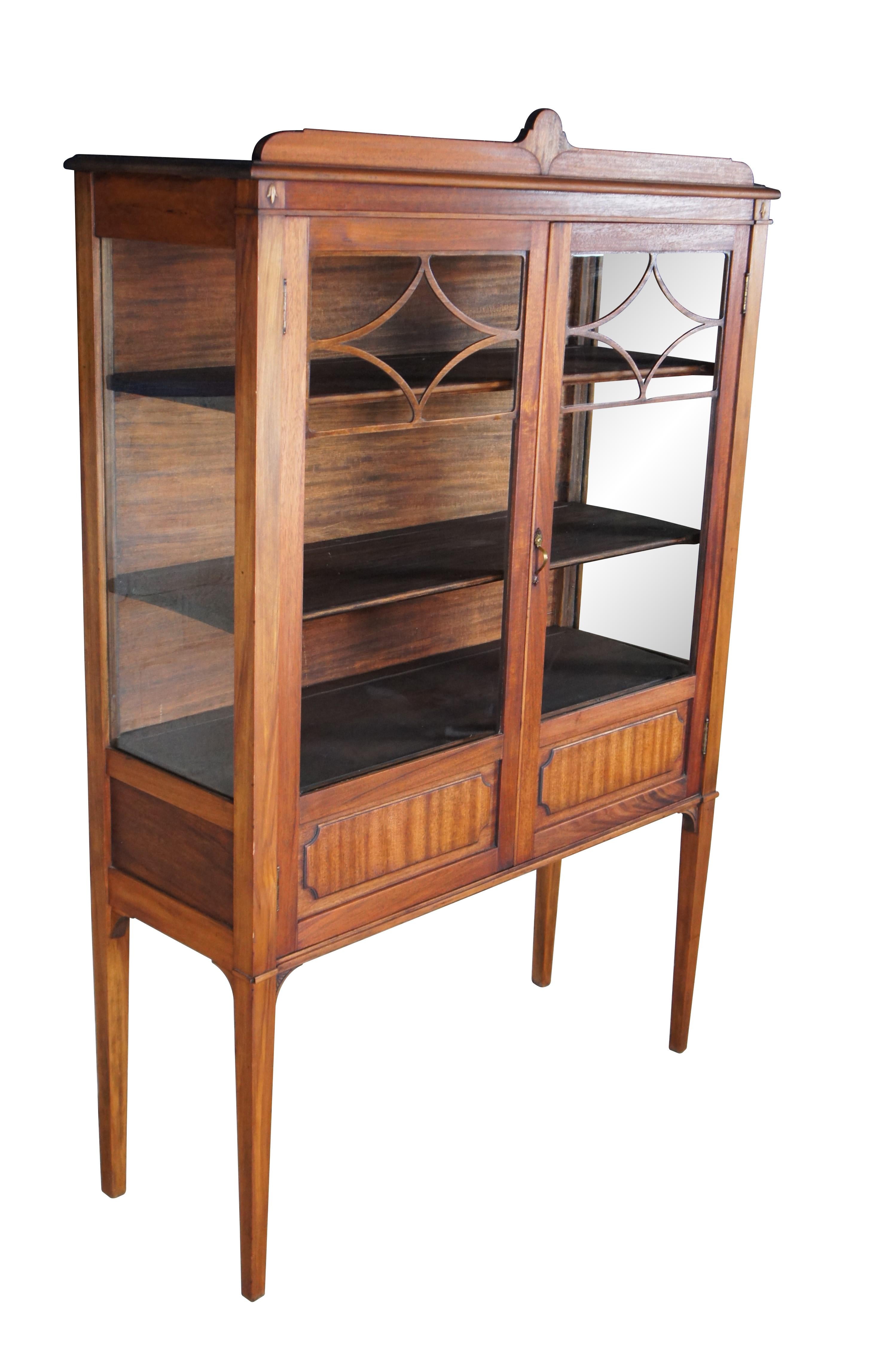 Antique curio china cabinet / bookshelf / show case / cupboard or vitrin.  Made of walnut featuring long tapered legs that support fretwork and paneled doors that open to three shelves with plate grooves and lower storage area.

Dimensions:

42