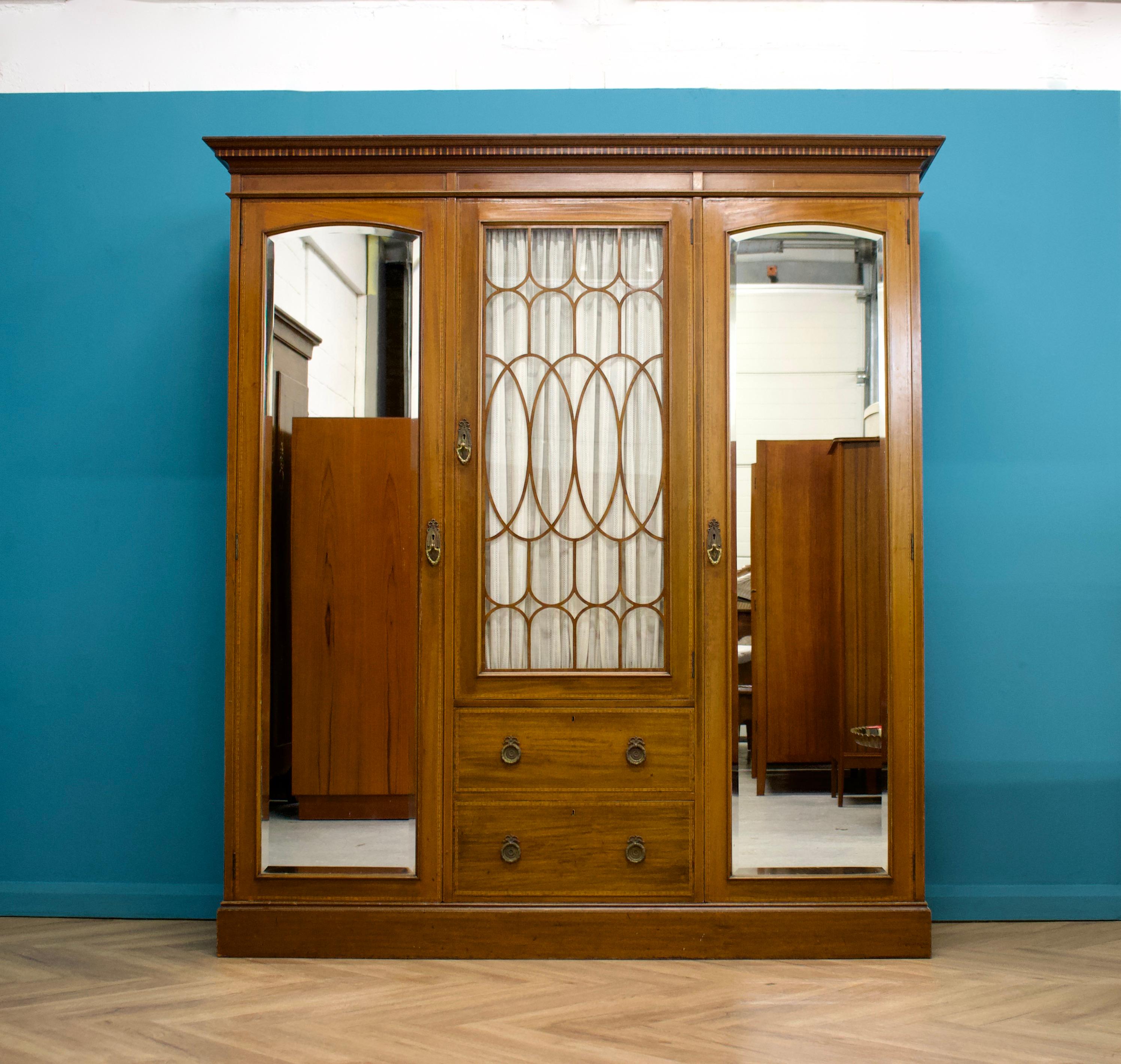 An impressive quality Edwardian compactum wardrobe made by the quality furniture makers Waring and Gillow

The exterior is in very good condition - there are two beveled mirrored doors, a glass door to the middle (we have replaced the glass with