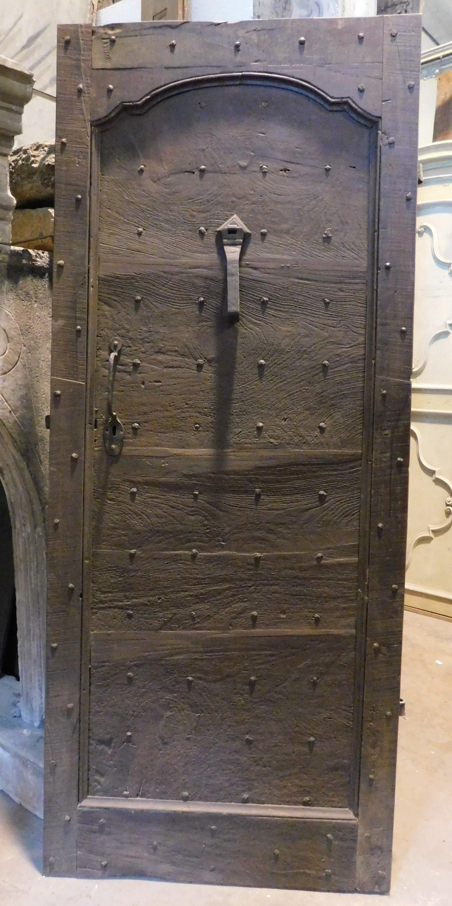 Ancient entrance door, rustic style studded but carved in walnut, of Piedmontese origin (northern Italy), hand-built in the 18th century, ideal for the entrance of country or mountain houses, but also ideal in cellars and wine cells, beautiful