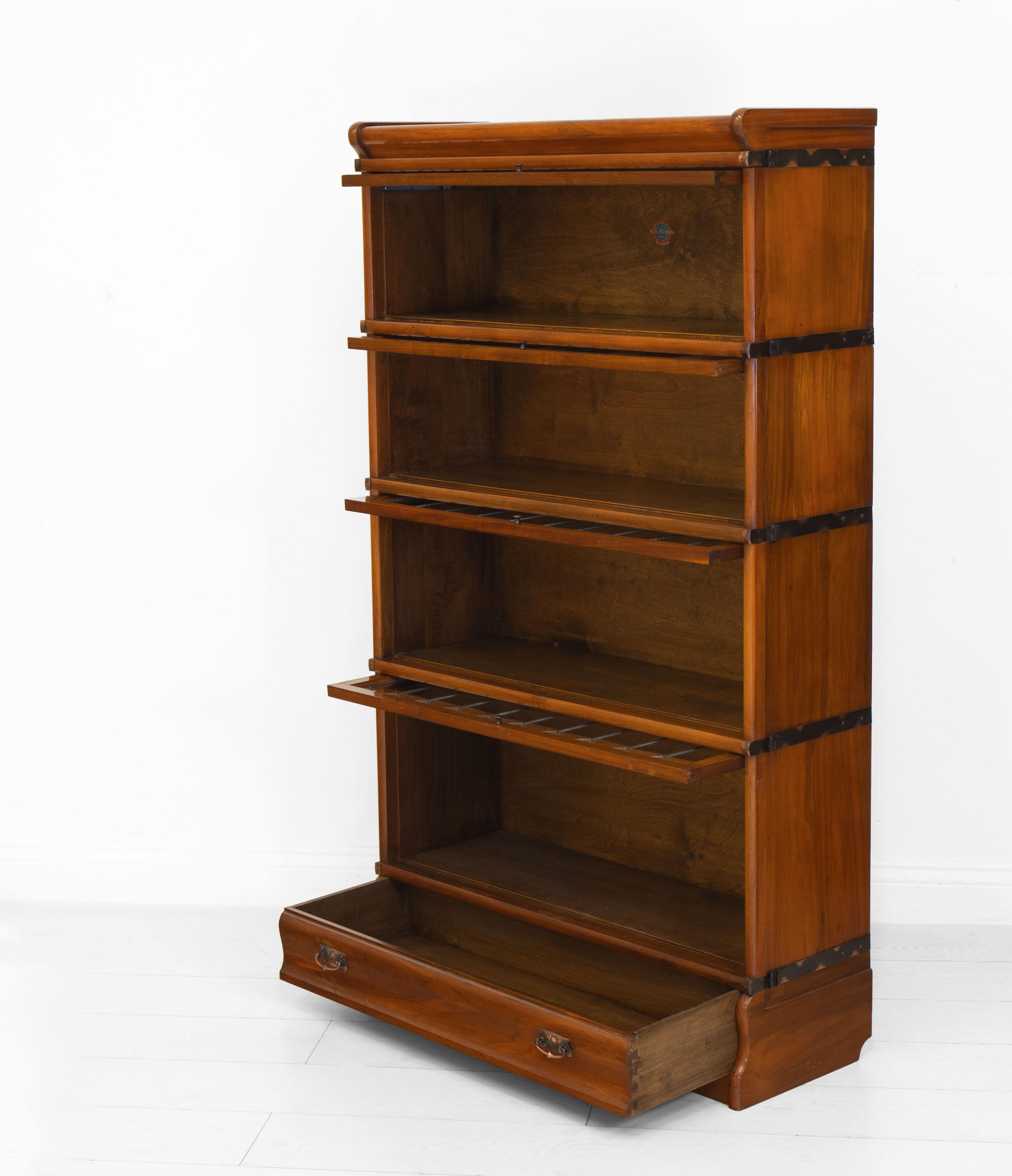 An English antique solid walnut four sectional bookcase with drawer by Globe Wernicke, England. Transfer label to one section. circa 1905.

Made in solid walnut with copperised metal side fittings and handles on both bookcase and drawer. The