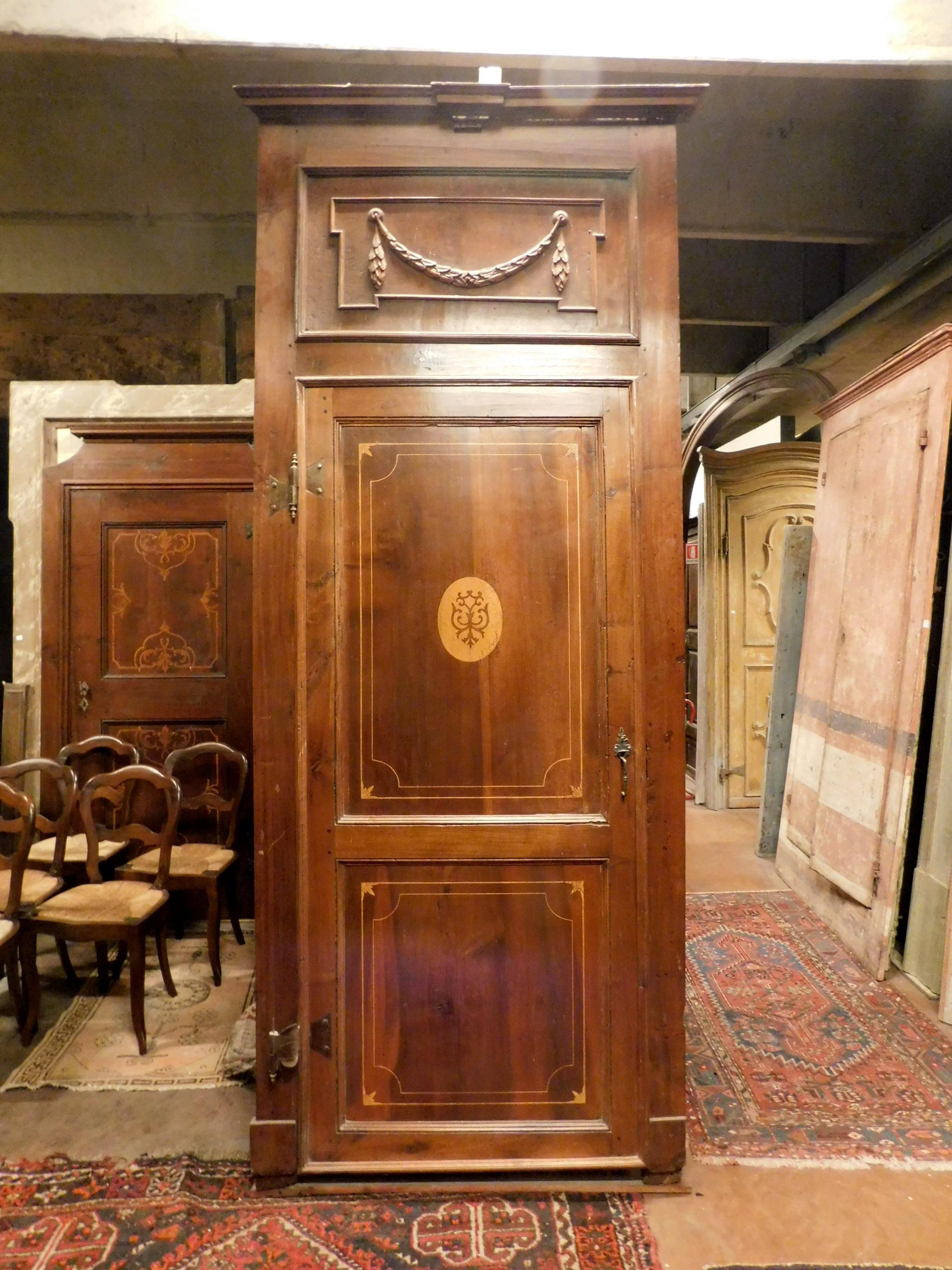 Antique walnut door with hand-carved inlays, complete with frame and original irons. Elegant interior door from an elegant building in northern Italy. Versatile thanks to a sober and clean style, it is well suited to many types of homes. built in