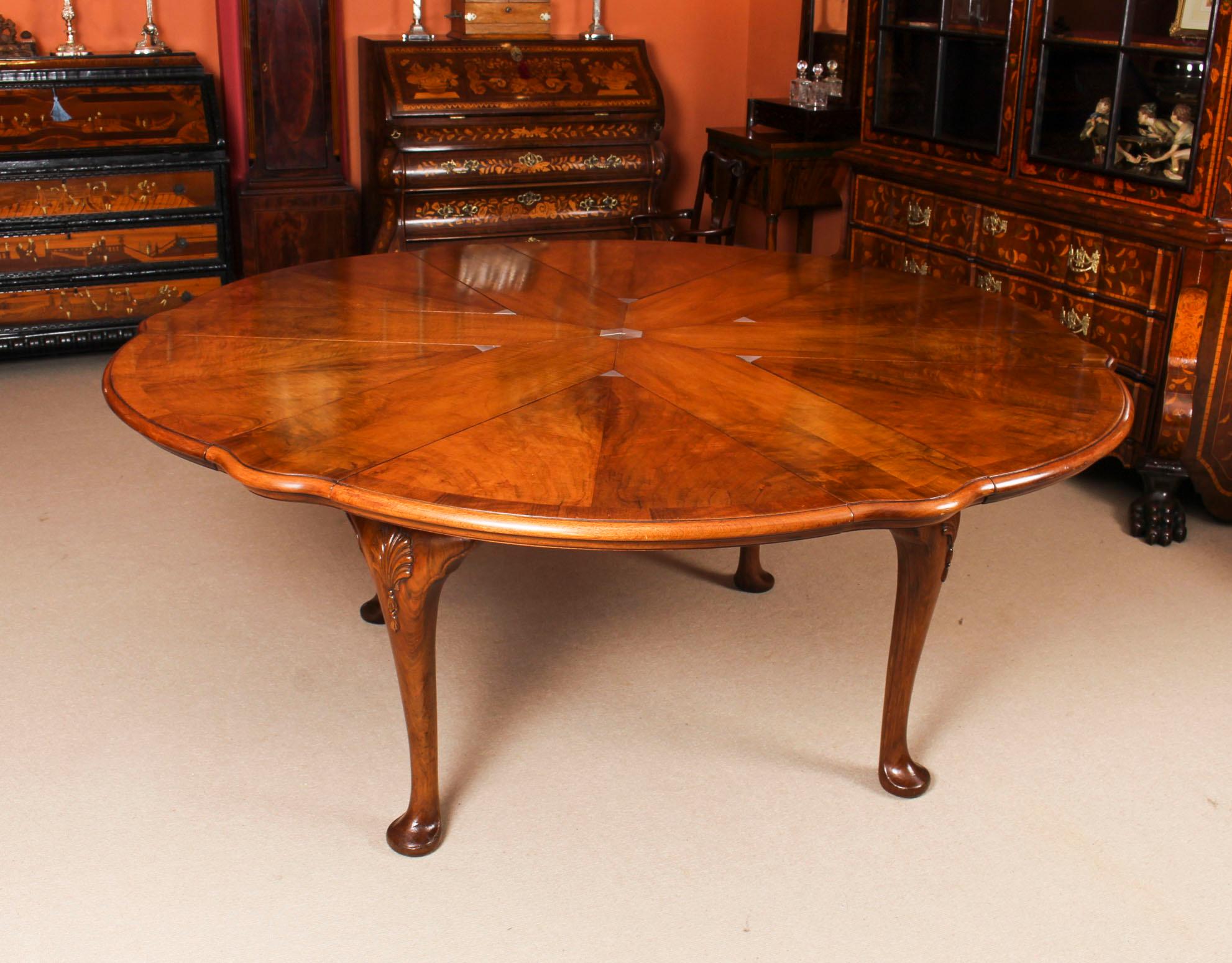 This is a important and rare Queen Anne revival walnut jupe action dining table by Gillows, with eight cabriole dining chairs, all dating from the late 19th century.

The amazing table features a shaped circular crossbanded top with a moulded