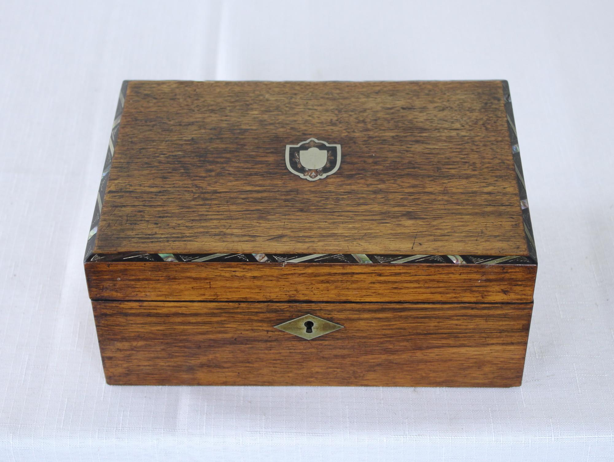 A Victorian ladies sewing box with geometric mother of pearl inlay around the top and a mother of pearl inlay medallion at the center. Small compartments in the interior removable shelf, some with silk box tops.