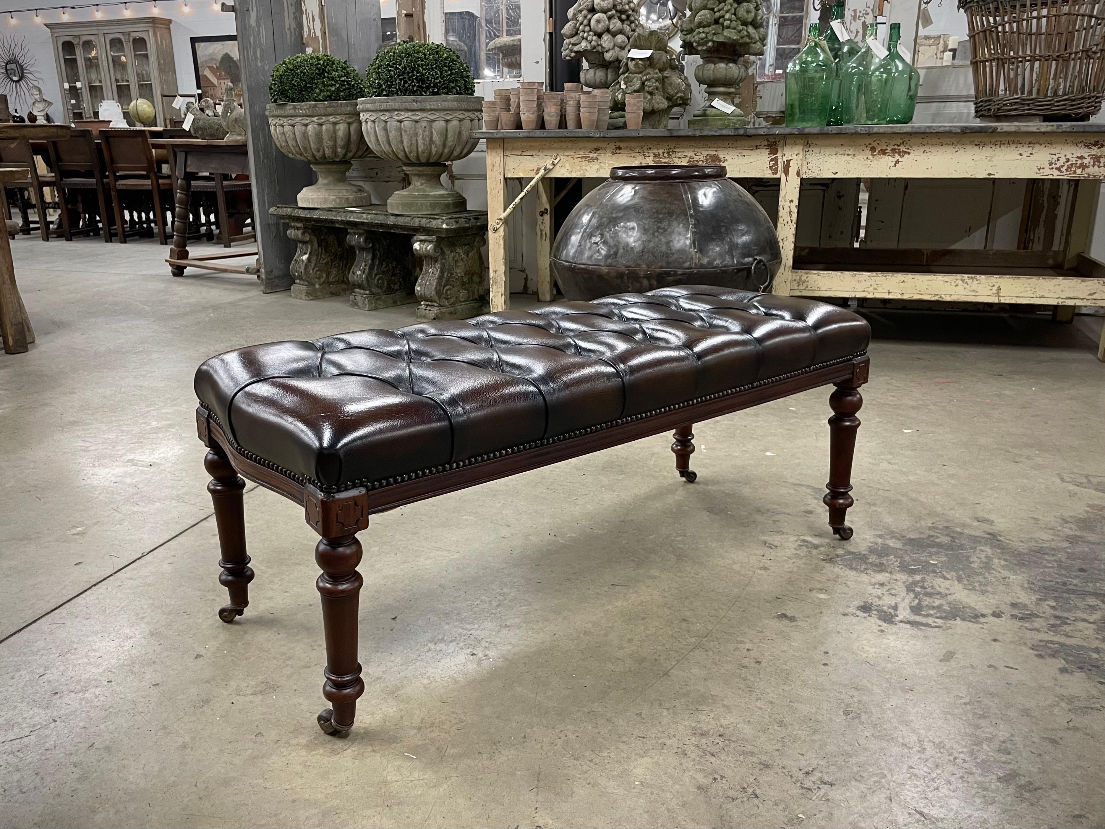Beautiful walnut studded bench with turned legs and casters. This chesterfield bench has been newly upholstered in rich tufted chocolate brown leather. it is in wonderful condition.

Perfect for the end of a bed or extra seating. Can also be used as