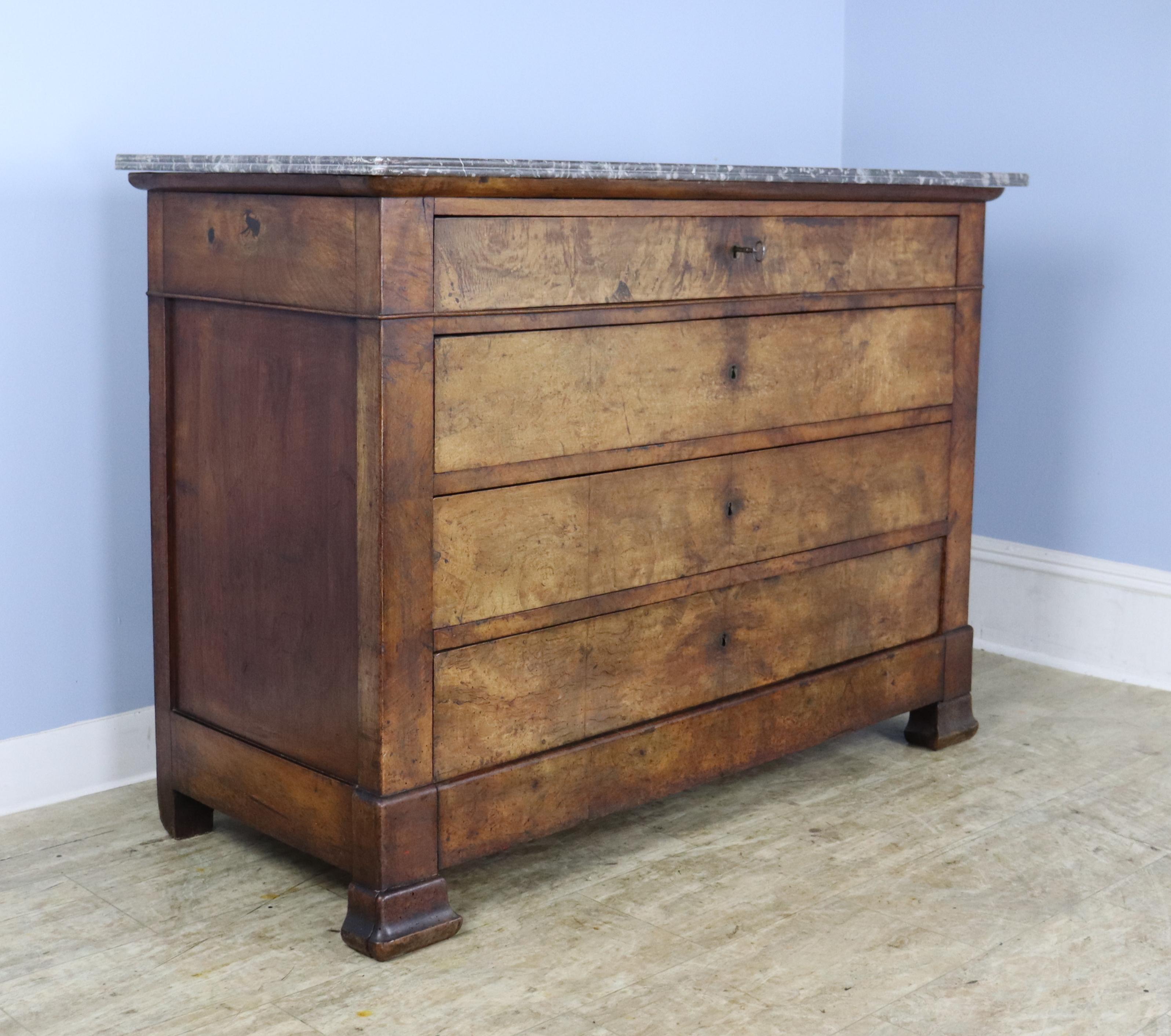 A classic Louis Philippe commode in dramtically grained walnut.  Four wide drawers which all open with the same key are quite clean inside and slide easily.  The walnut has very good color and patina,  with some fading in areas.  Marble is in nice
