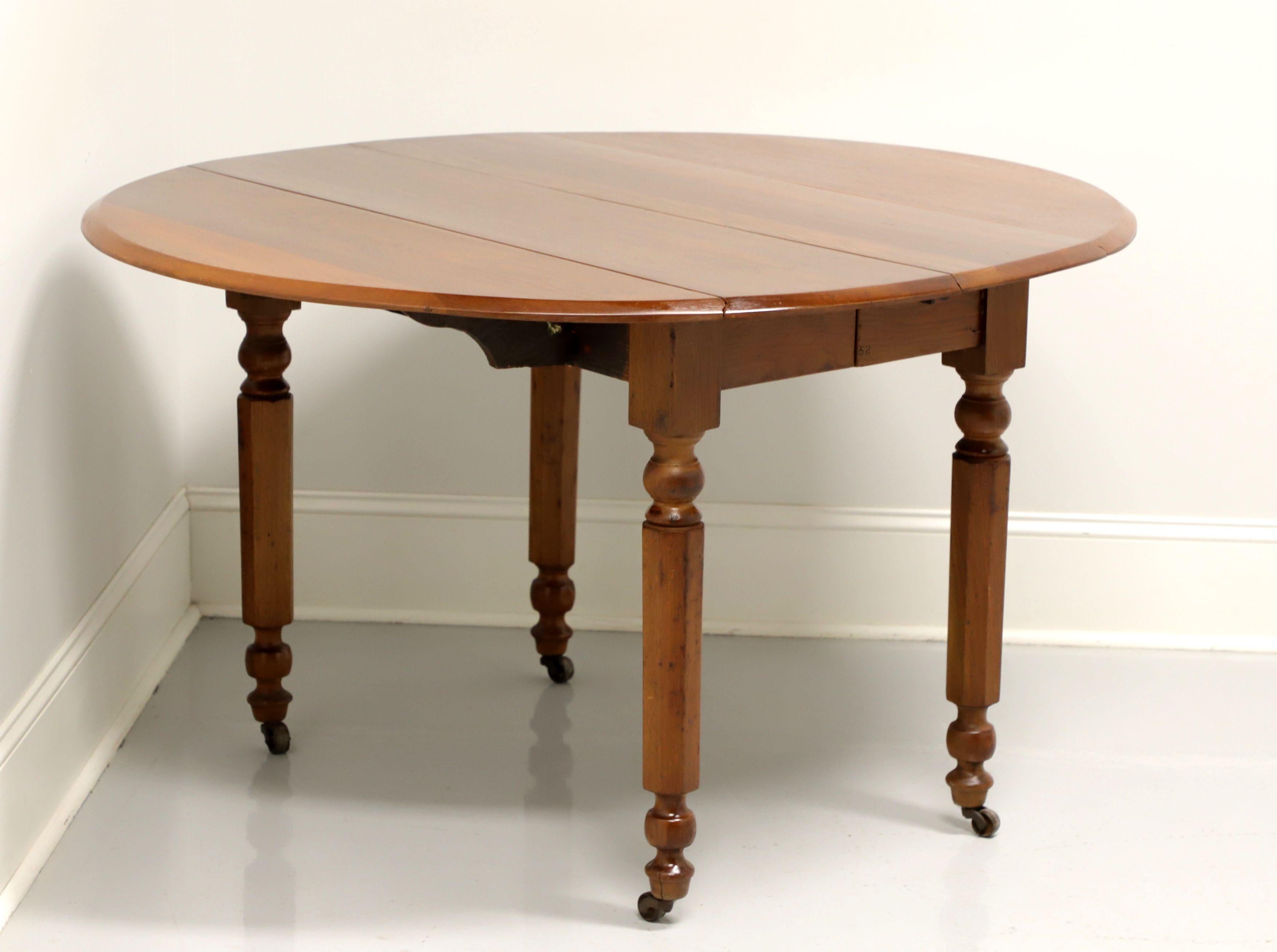 An antique American drop leaf dining table, unbranded. Solid walnut with brass casters. Features a beveled edge, wood fold out arms to support drop leaves, turned and fluted legs with casters. Table does expand on wood expansion sliders to