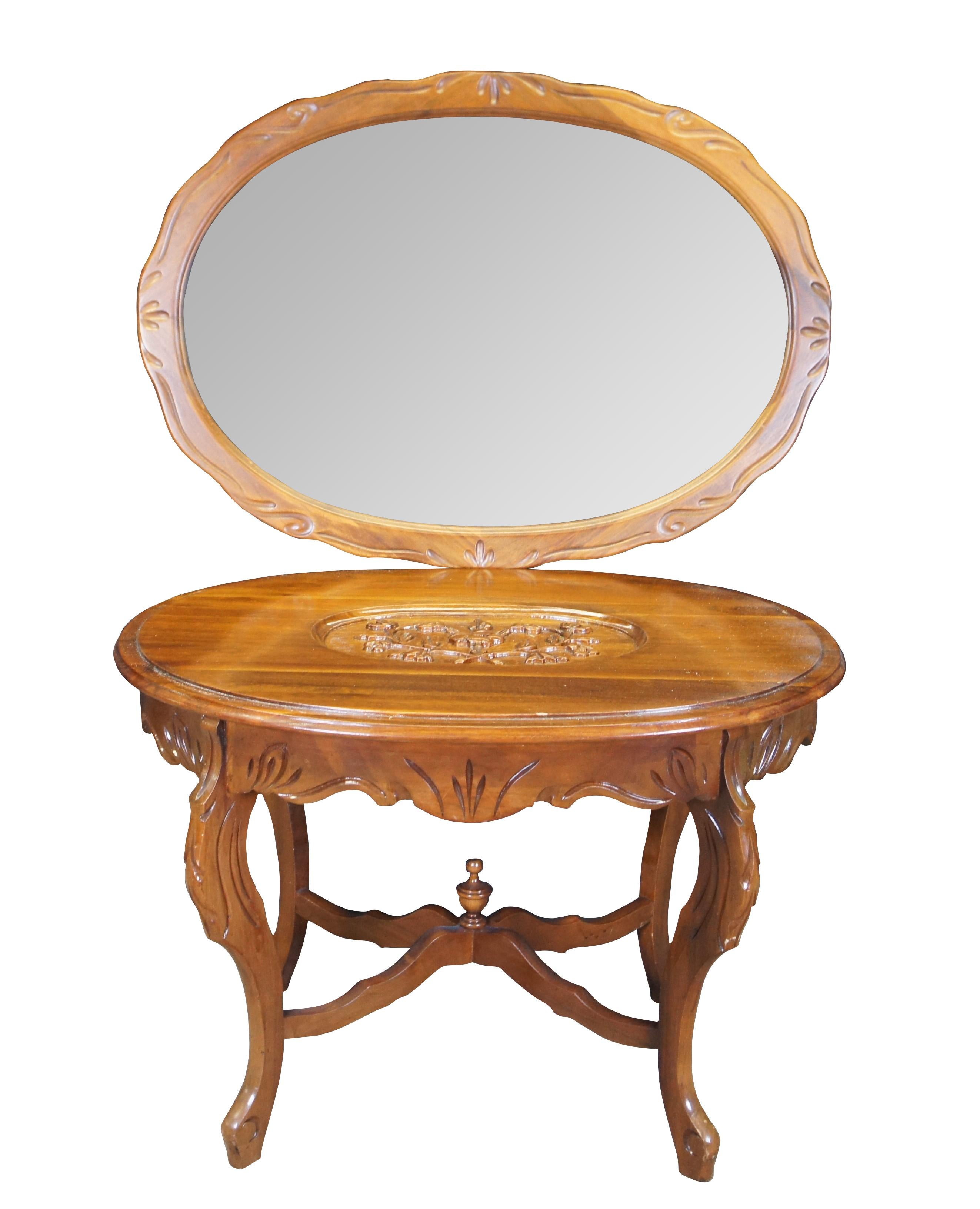 Antique American walnut carved tea coffee cocktail table featuring a scalloped oval butler tray that sits over a high relief carved floral design.  The table is supported by carved and scrolled legs connected by X stretcher with trophy