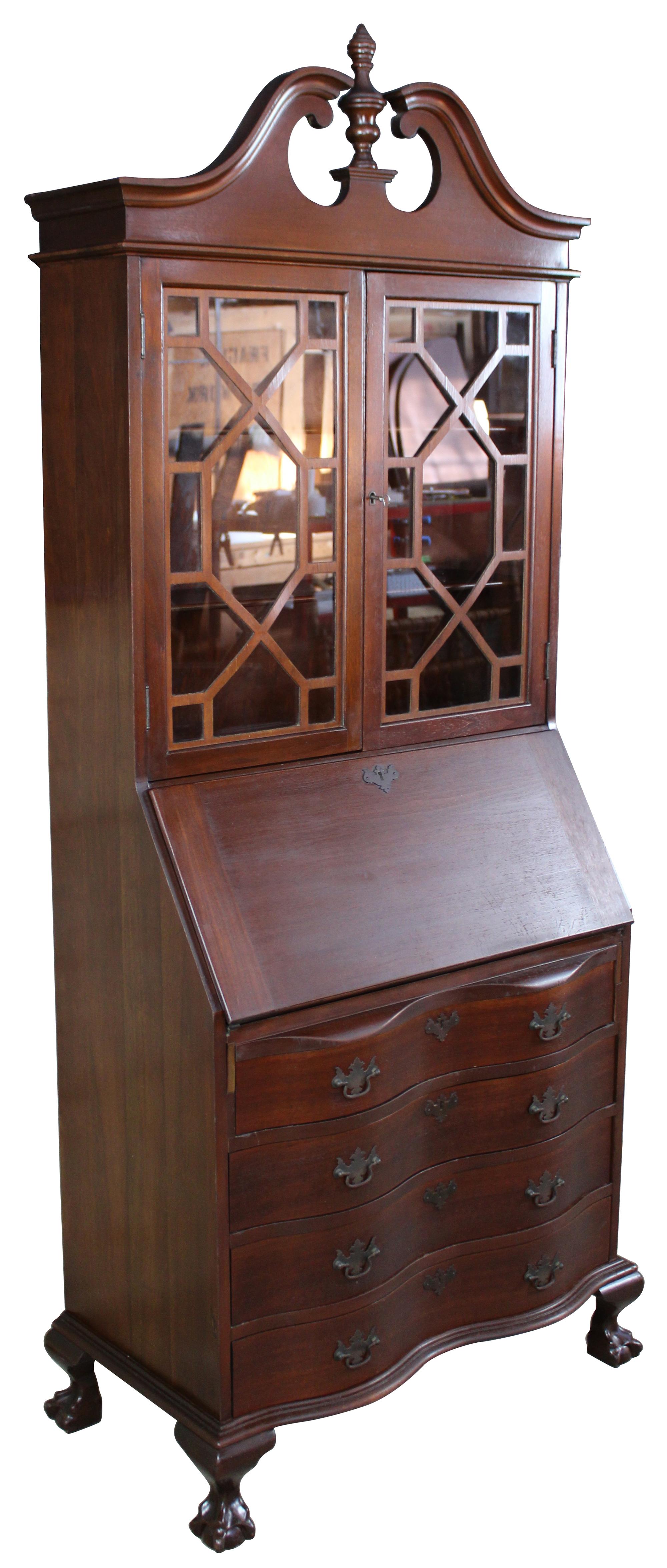 A gorgeous serpentine front one piece secretary desk. Made from American walnut. Interior opens to four drawers, pigeon holes and hidden compartments. Upper bookcase portion shows an open pediment with turned finial. Doors are glass with fretwork.