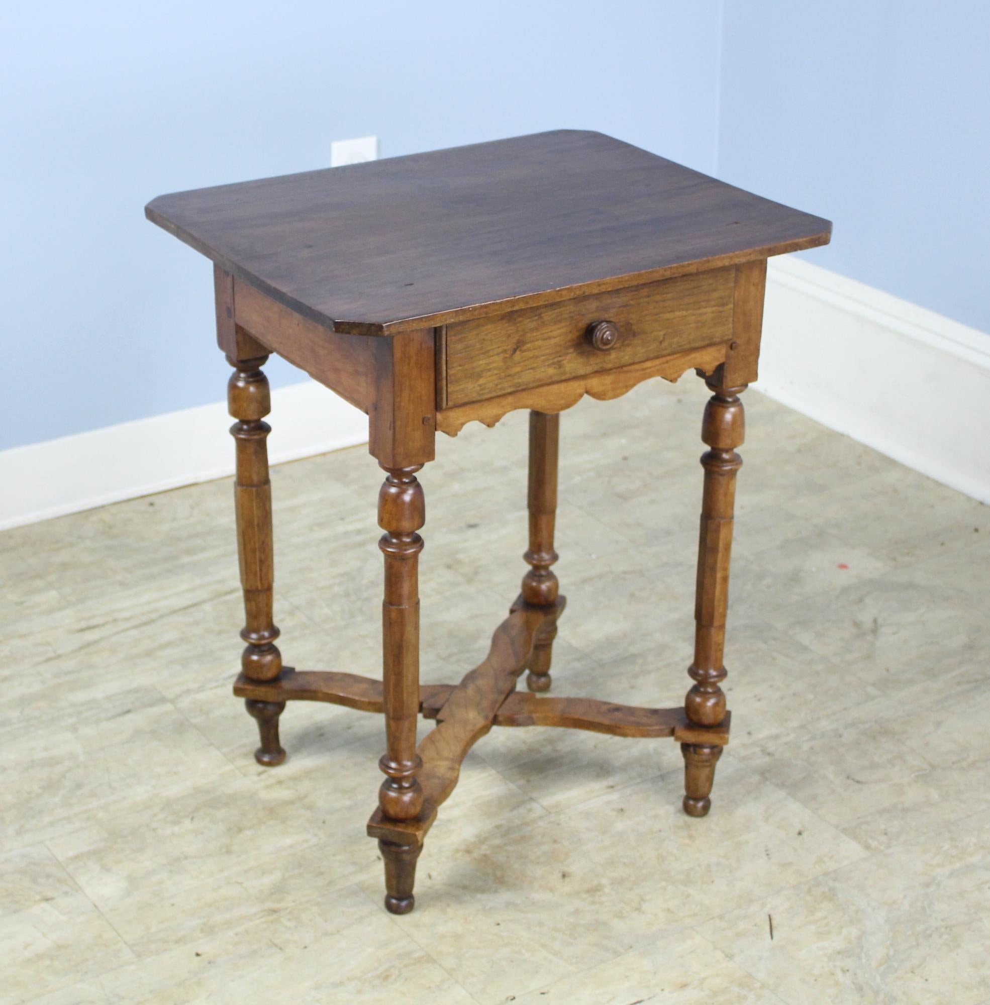 A splendid walnut side table with a single drawer and graceful turned legs. Charming shaped apron. Wonderful walnut grain and color and good patina. The shaped stretchers adds a note of whimsy.  Back leg has been replaced as is slightly different as