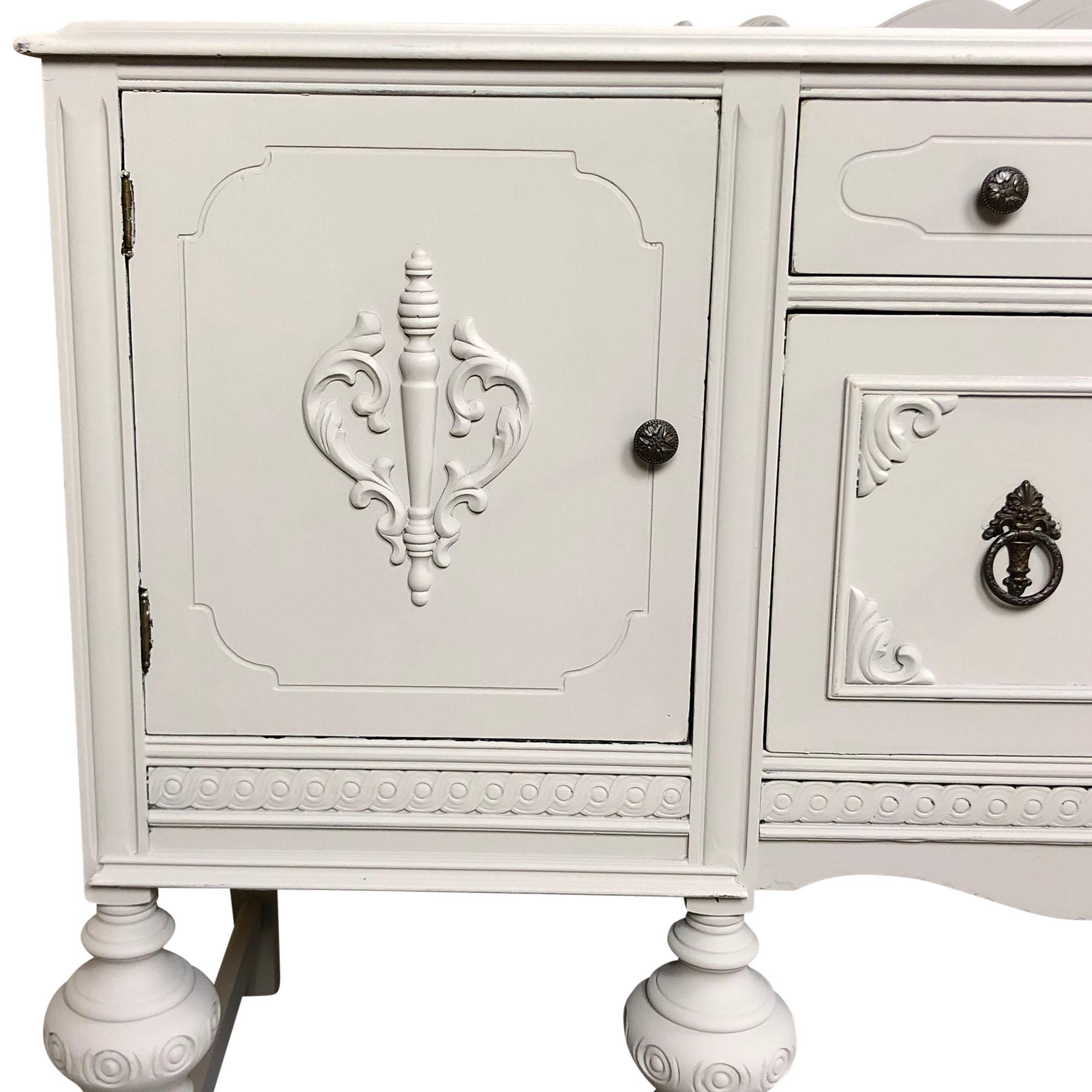 A lovely antique walnut sideboard has been updated with in an off-white chalk paint and slightly distressed edges. The sideboard is constructed of solid woods and veneers with well-crafted details throughout. Additionally, the sideboard has a low