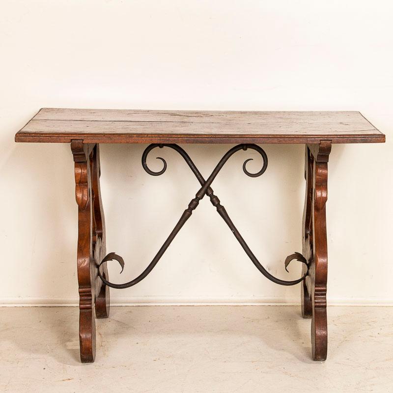 This handsome Spanish side table has a traditional carved lyre leg but made in the unique shape of swan heads. Note the left side had the date 1799 carved into the leg. The twisted wrought-iron stretchers add a wonderful contrast to the rich patina