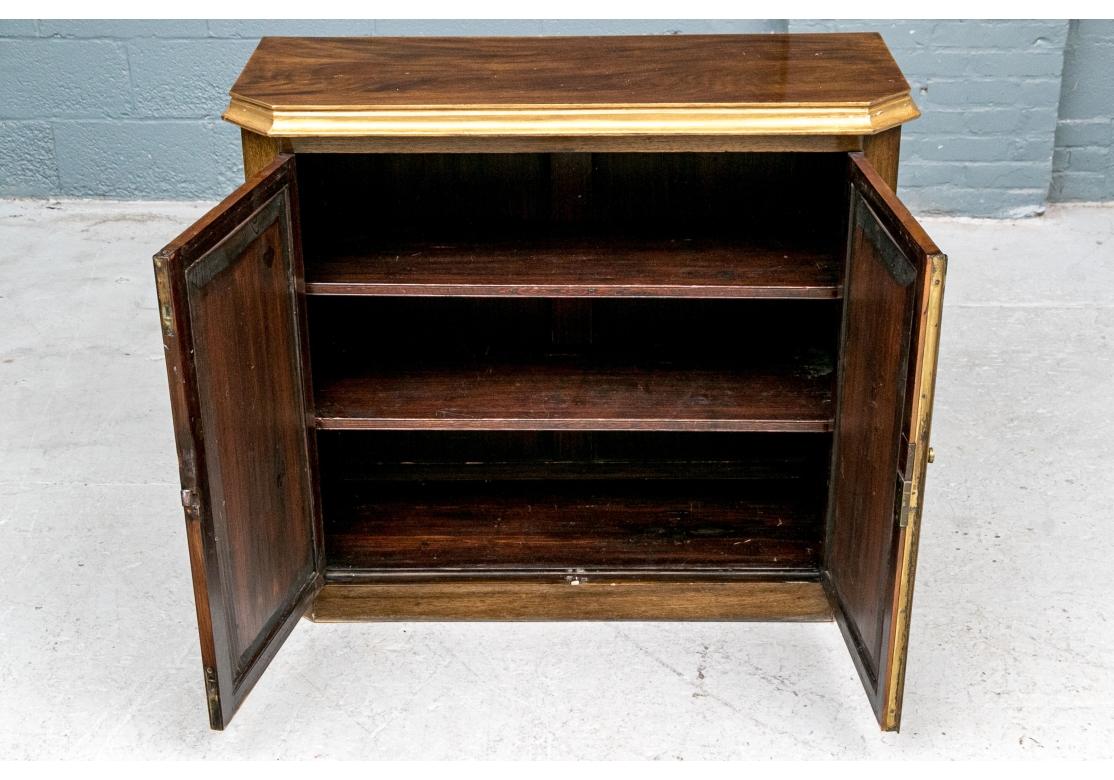 Armoire ancienne en noyer avec deux portes à garniture en métal doré qui s'ouvrent pour révéler deux étagères en bois réglables et amovibles. Le meuble comporte des portes à bandes croisées, des coins cantonnés, des garnitures à la feuille d'or, un