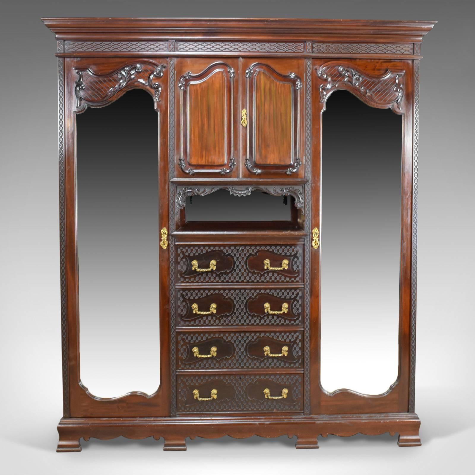 This is an antique wardrobe in carved mahogany, an English compactum dating to the Edwardian period, circa 1910.

Craftsmanship in a quality dark mahogany with a wax polished finish
Good consistent color throughout with a desirable aged