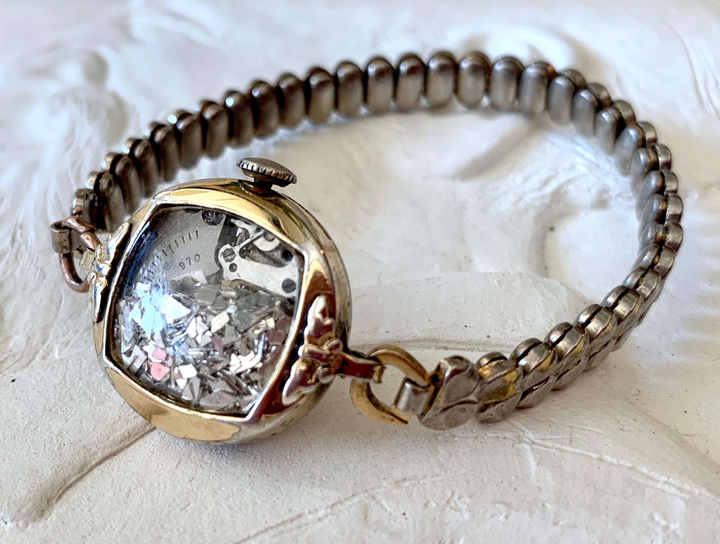 The Fairydust band is a non-functioning antique watch  a symbol, a talisman,
to hold the intention of staying present, neither dwelling in
the past nor looking toward the future. The fairydust inside
are mirror shards, a shattering of the