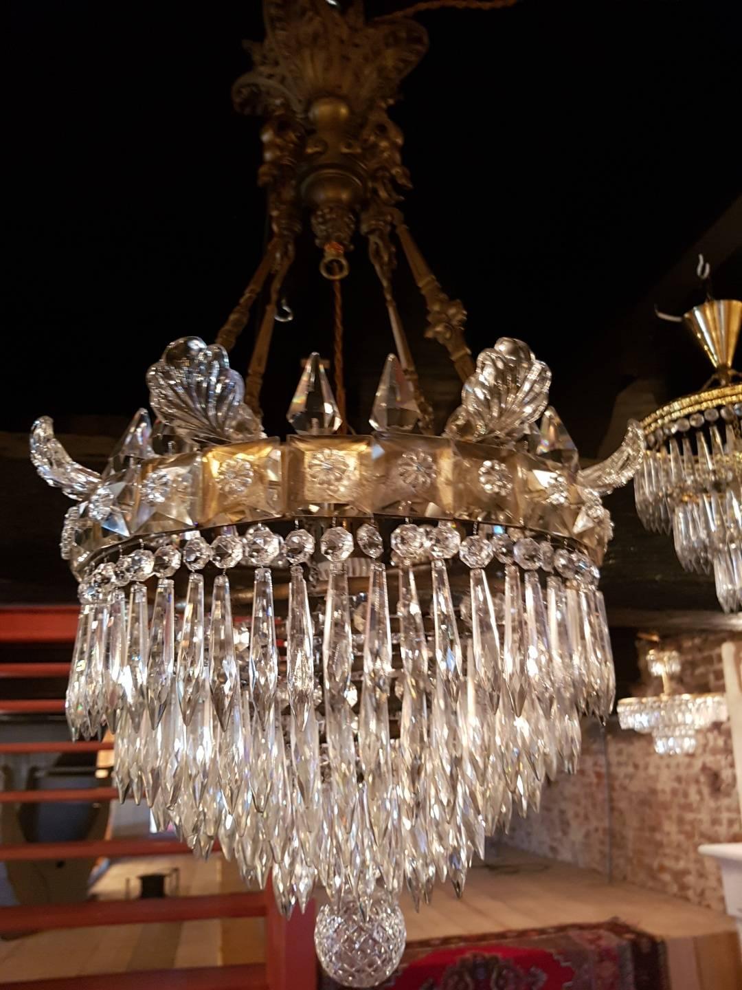 Antique waterfall chandelier with a waterfall of cut-glass. At the top of the ring are crystal pinnacles and glass ornaments. The ring itself is decorated with square stiff pieces of glass. The top of the chandelier and the hanging construction is