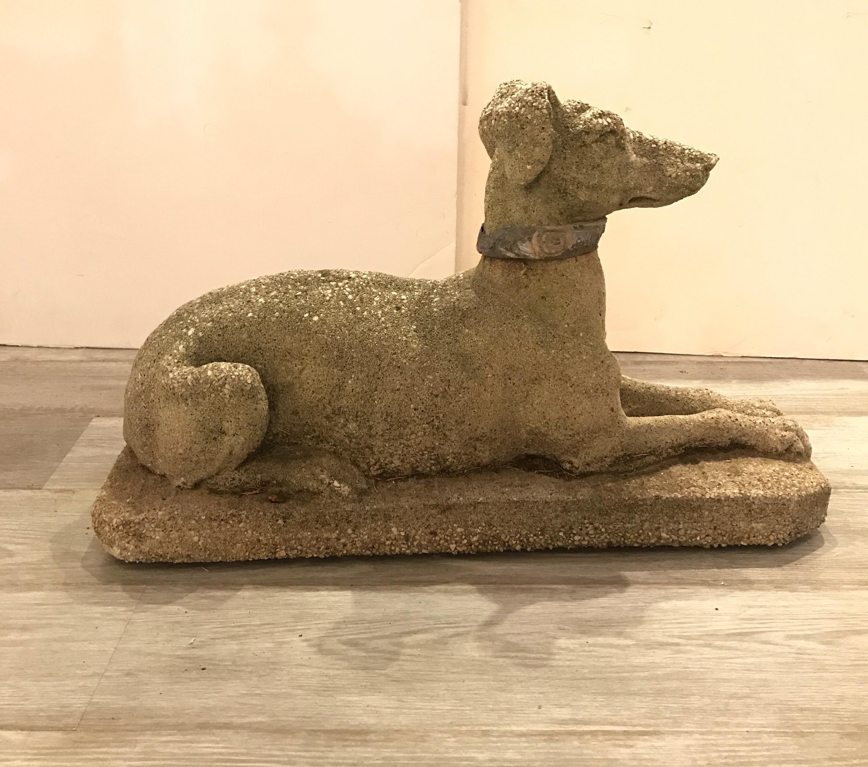 A handsome early 20th century cast cement garden sculpture of a dog. The dog, in the form of a resting Whippet with an lead collar. Original finish and texture.